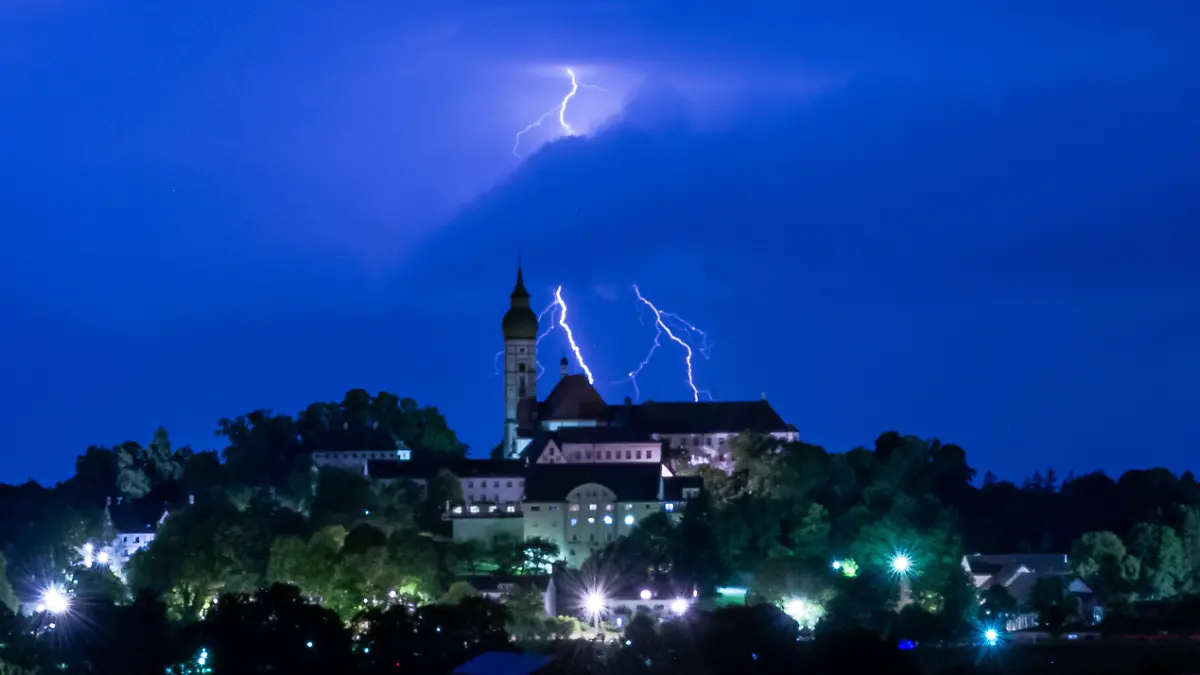 11.07.2023, Bayern, Andechs: Ein Gewitter entlädt sich mit Blitz und Donner hinter der Kulisse des Kloster Andechs auf dem Heiligen Berg. Foto: Peter Kneffel/dpa +++ dpa-Bildfunk +++