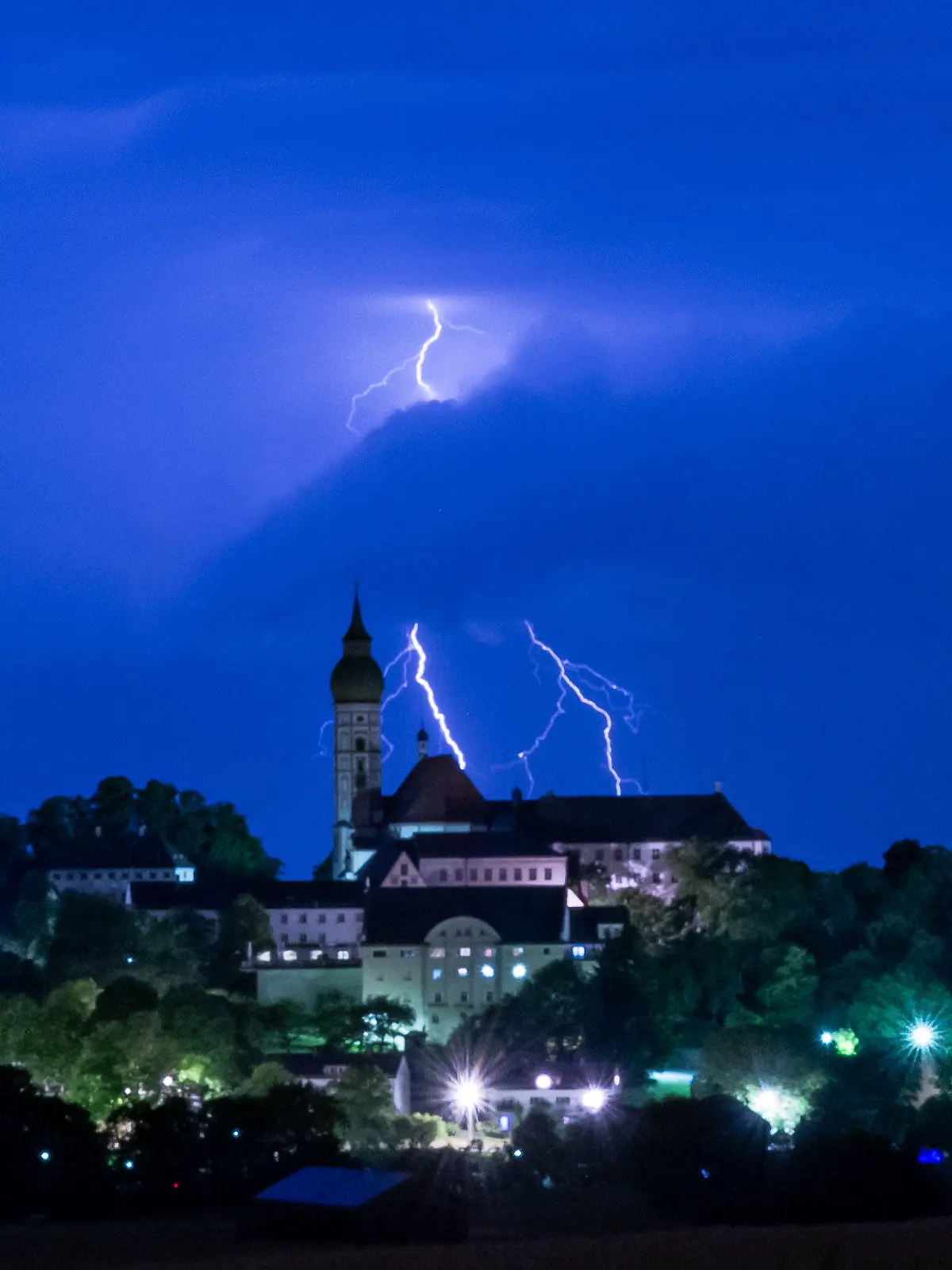 11.07.2023, Bayern, Andechs: Ein Gewitter entlädt sich mit Blitz und Donner hinter der Kulisse des Kloster Andechs auf dem Heiligen Berg. Foto: Peter Kneffel/dpa +++ dpa-Bildfunk +++