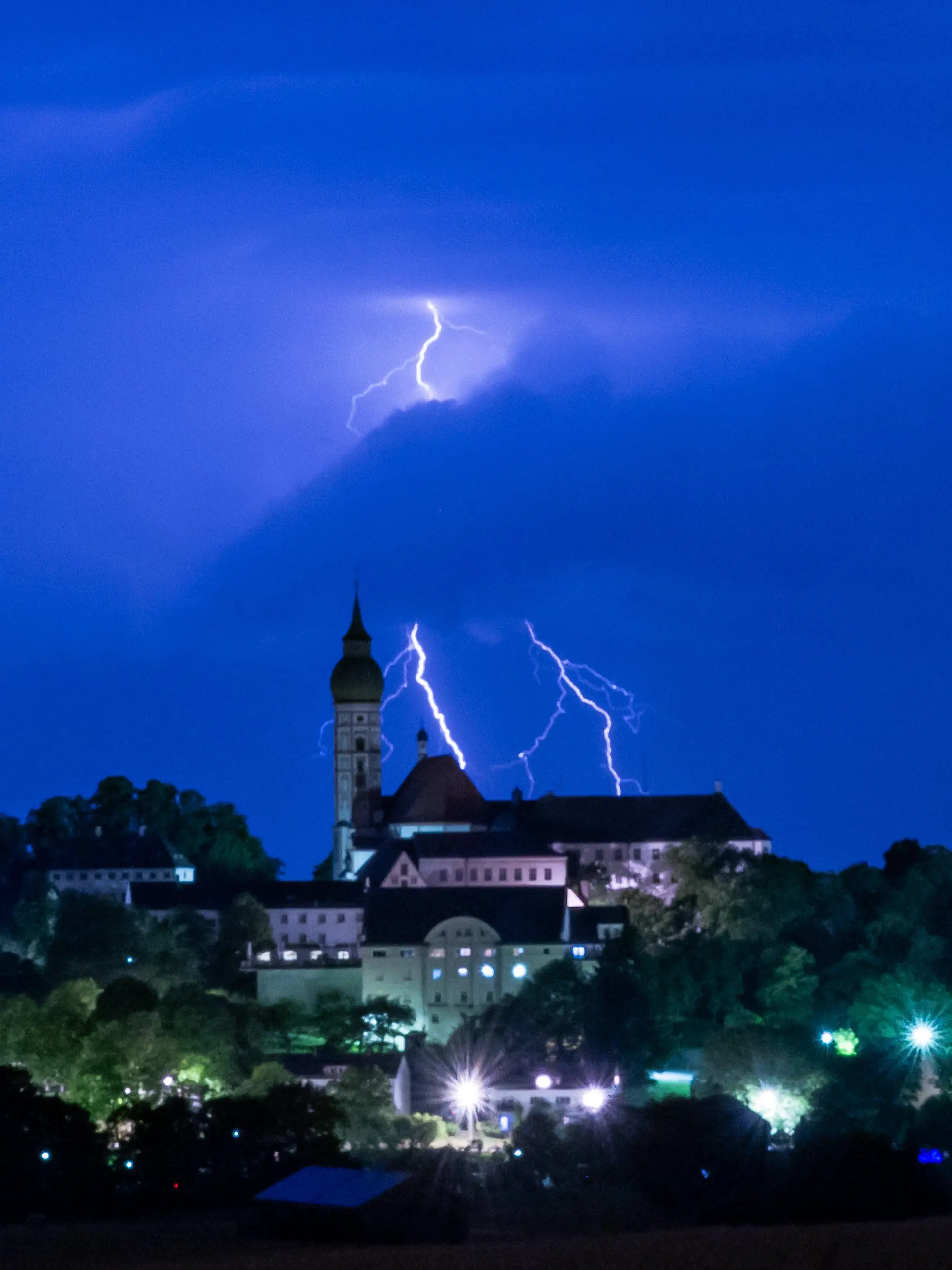 11.07.2023, Bayern, Andechs: Ein Gewitter entlädt sich mit Blitz und Donner hinter der Kulisse des Kloster Andechs auf dem Heiligen Berg. Foto: Peter Kneffel/dpa +++ dpa-Bildfunk +++