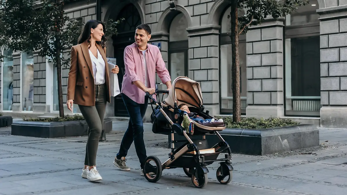 Happy family with baby in a stroller walking down the street and shopping