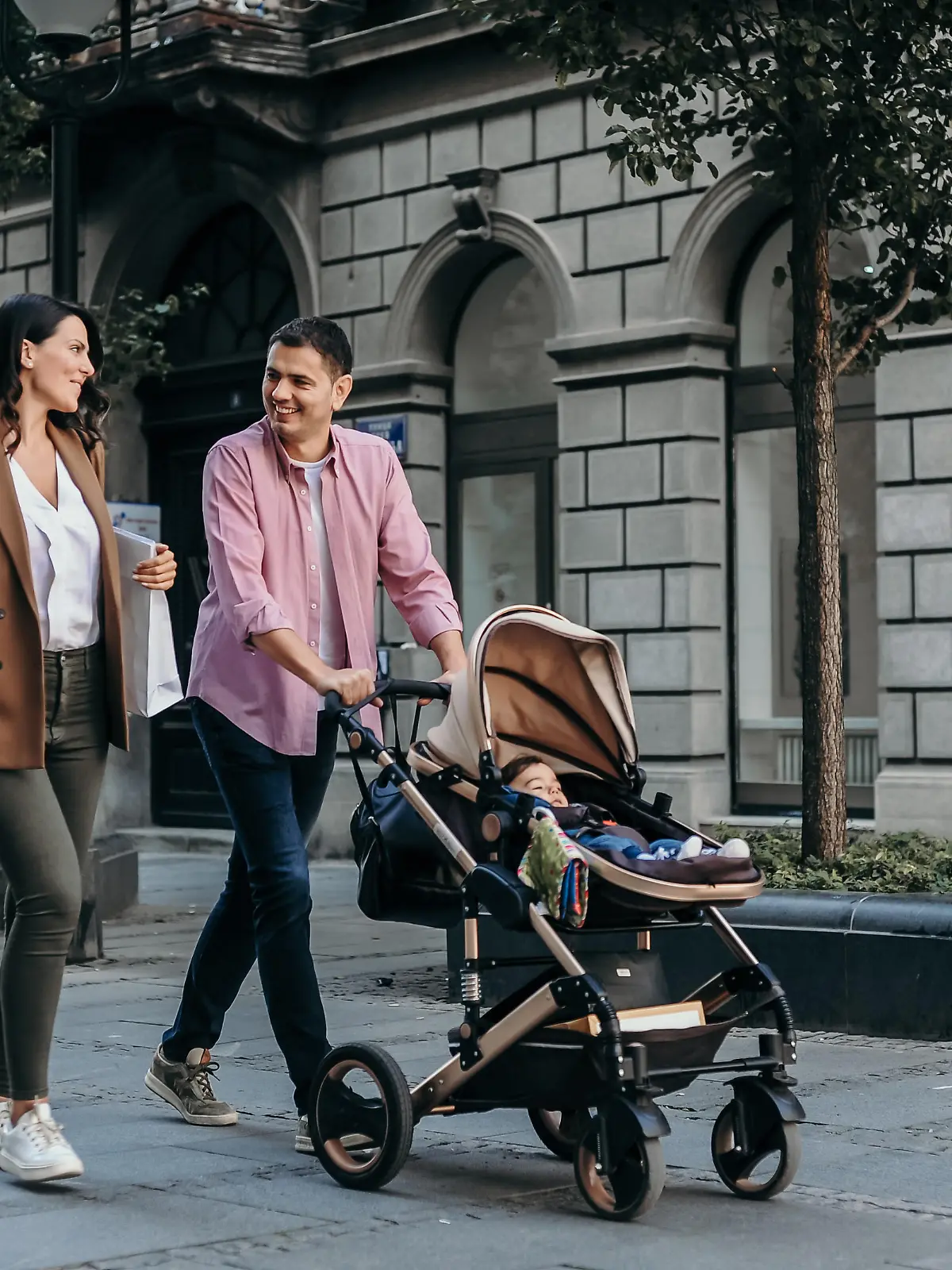 Happy family with baby in a stroller walking down the street and shopping