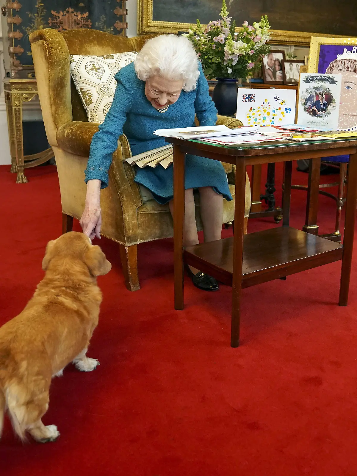 ARCHIV - 04.02.2022, Großbritannien, Windsor: Königin Elizabeth II. streichelt einen ihrer Hunde, einem Corgi namens Candy, während sie Erinnerungsstücke von ihrem Goldenen und Platin Thronjubiläum im Eichensaal von Schloss Windsor betrachtet. (zu dpa "Queens liebste Hunderasse im Königreich wieder auf dem Vormarsch") Foto: Steve Parsons/PA Wire/dpa +++ dpa-Bildfunk +++