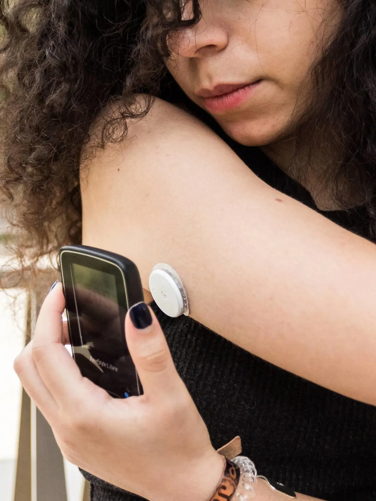 A young diabetic woman equipped with a glucose sensor and Freestyle Libre scanner. The scanner can just be flashed at the sensor on the back of the arm to instantly measure blood sugar levels. || Modellfreigabe vorhanden