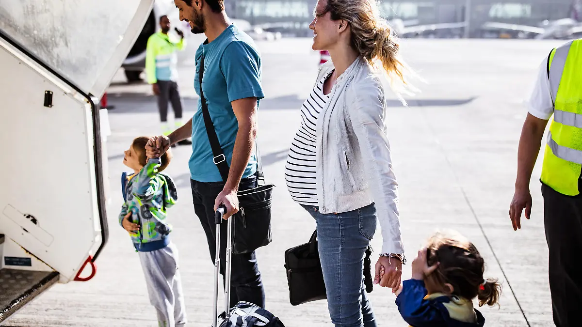 Young happy family holding hands while about to board into an airplane. Focus is on woman.
