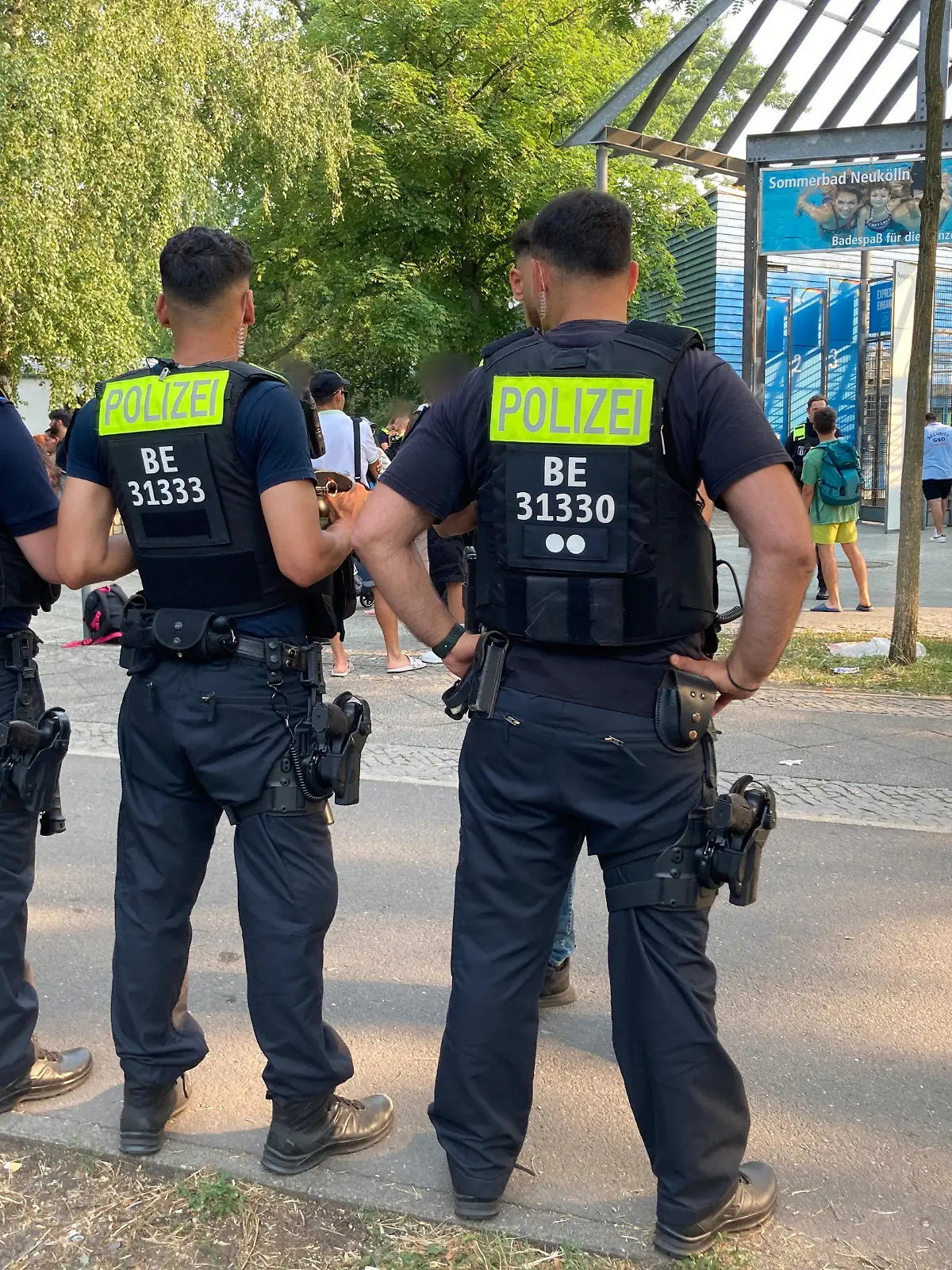 09.07.2023, Berlin: Polizisten stehen vor dem Eingang des Sommerbad in Neukölln. Das Berliner Freibad wird wegen seiner Lage am Columbiadamm auch Columbiabad genannt. Zum wiederholten Male war ein Berliner Freibad wegen Rangeleien und renitenter Besucher frühzeitig geschlossen und geräumt worden. Foto: Carioline Bock/dpa - ACHTUNG: Person(en) wurde(n) aus rechtlichen Gründen gepixelt +++ dpa-Bildfunk +++