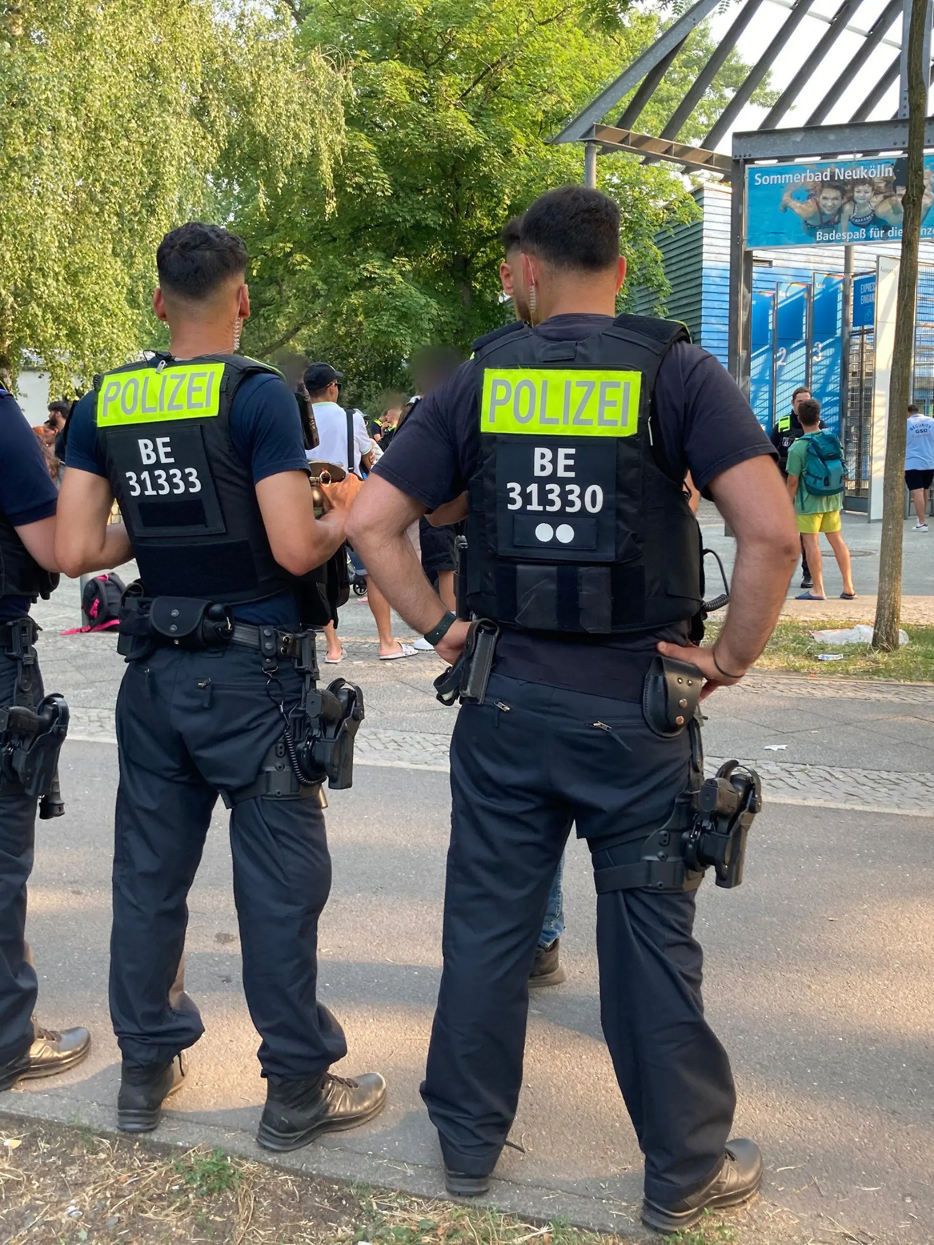 09.07.2023, Berlin: Polizisten stehen vor dem Eingang des Sommerbad in Neukölln. Das Berliner Freibad wird wegen seiner Lage am Columbiadamm auch Columbiabad genannt. Zum wiederholten Male war ein Berliner Freibad wegen Rangeleien und renitenter Besucher frühzeitig geschlossen und geräumt worden. Foto: Carioline Bock/dpa - ACHTUNG: Person(en) wurde(n) aus rechtlichen Gründen gepixelt +++ dpa-Bildfunk +++
