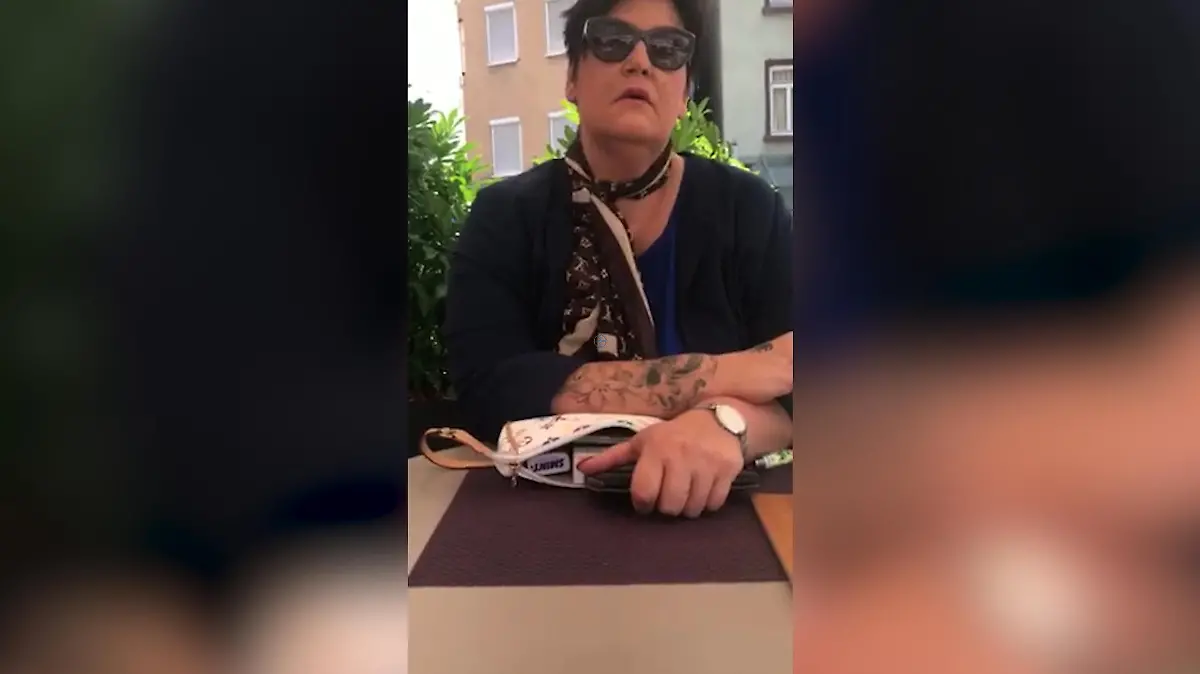 Eine Frau sitzt in einem Café auf der Terrasse und raucht.