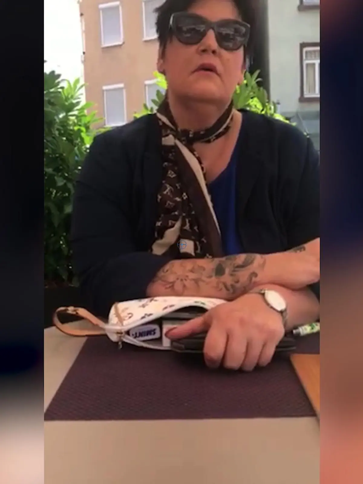 Eine Frau sitzt in einem Café auf der Terrasse und raucht.