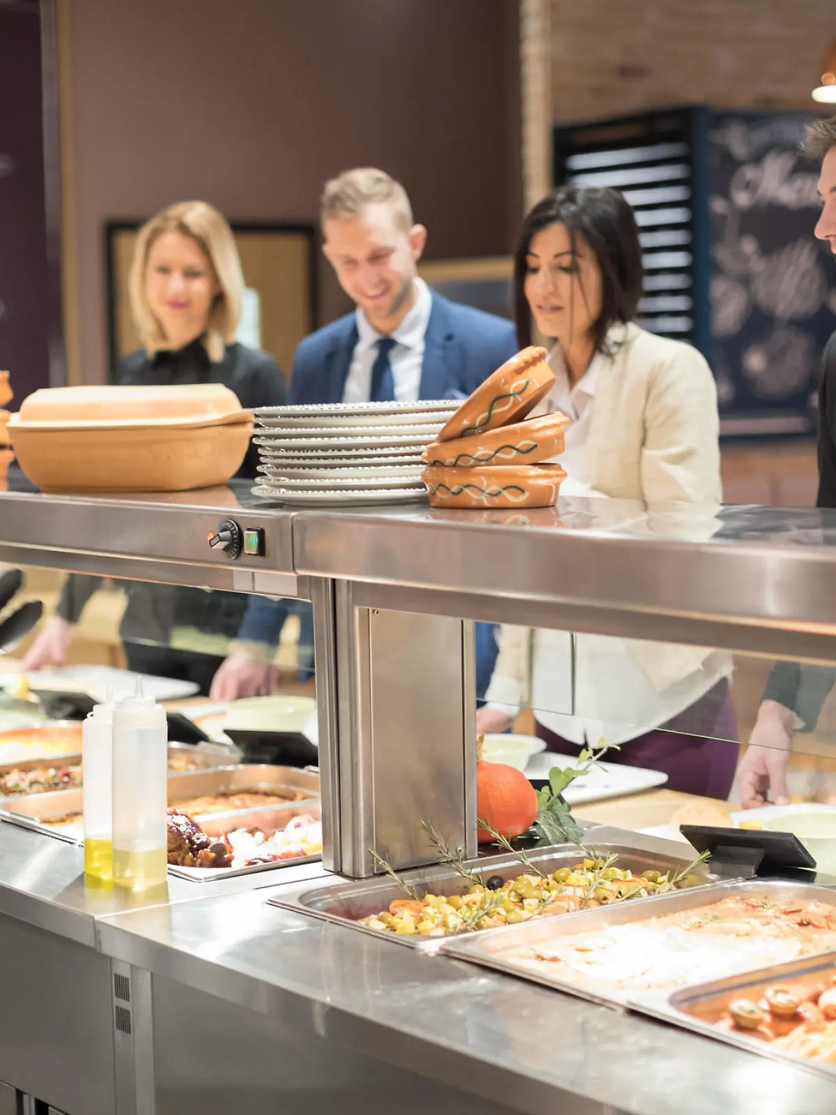 Cafeteria worker serving lunch, people waiting in line