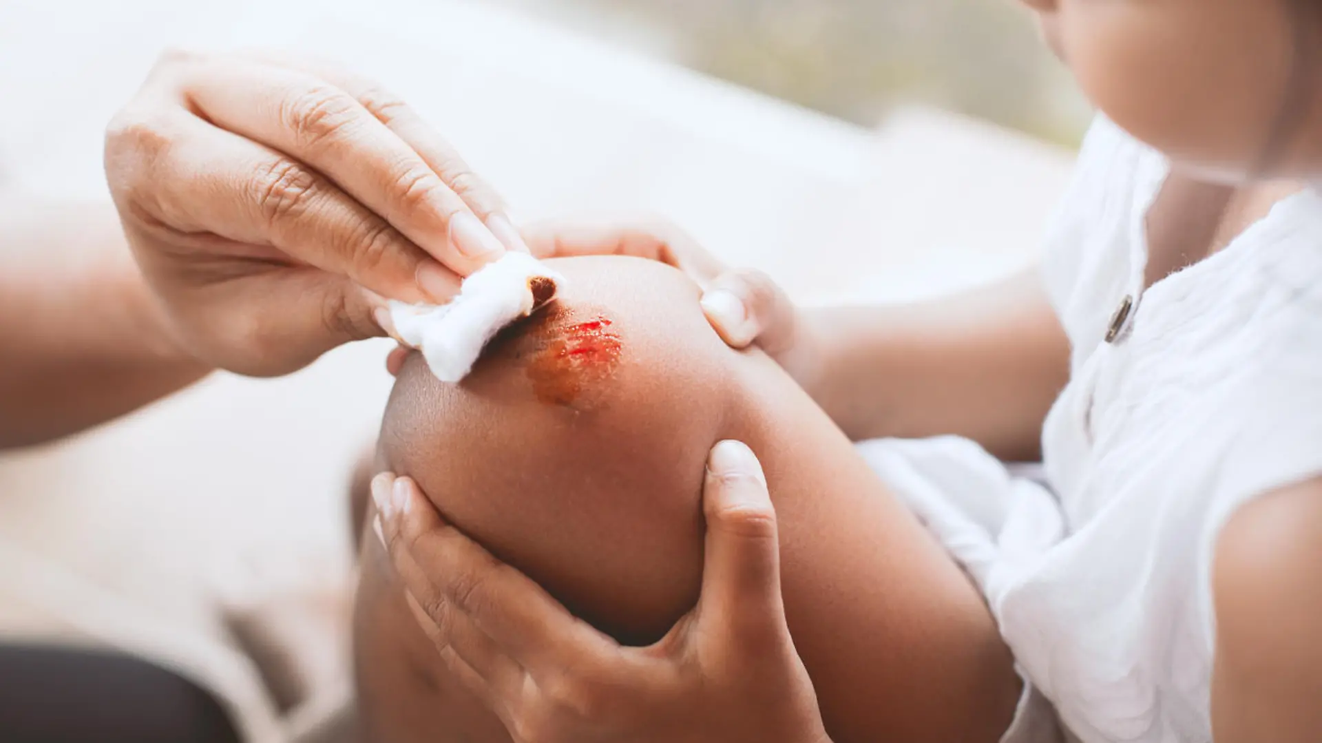 Parent helping her child perform first aid knee injury after she has been an accident