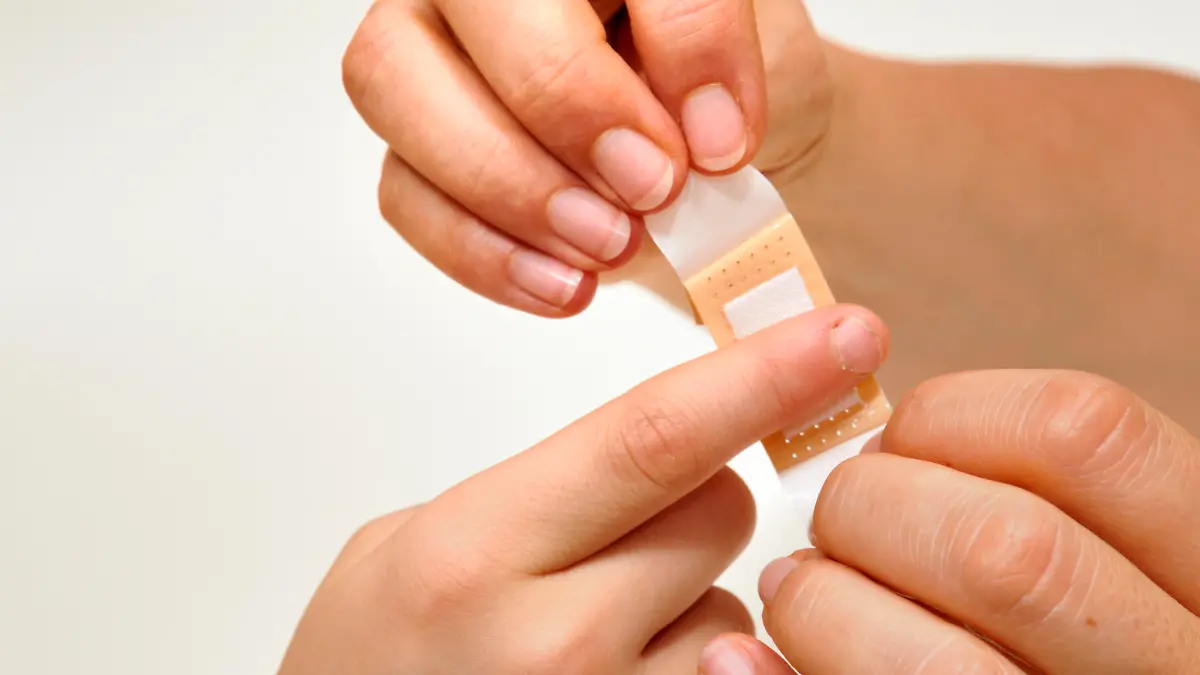 Pflaster wird an verletzter Hand angebracht