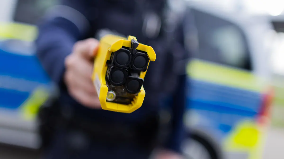 PRODUKTION - 07.03.2024, Nordrhein-Westfalen, Düsseldorf: Ein Polizist hält einen Taser (Distanzelektroimpulsgerät) in den Händen. Das Gerät sendet nach Abschuss zweier Elektroden Stromimpulse ab. (zu dpa: «Polizei greift öfter zum Taser - drückt aber selten ab») Foto: Rolf Vennenbernd/dpa +++ dpa-Bildfunk +++