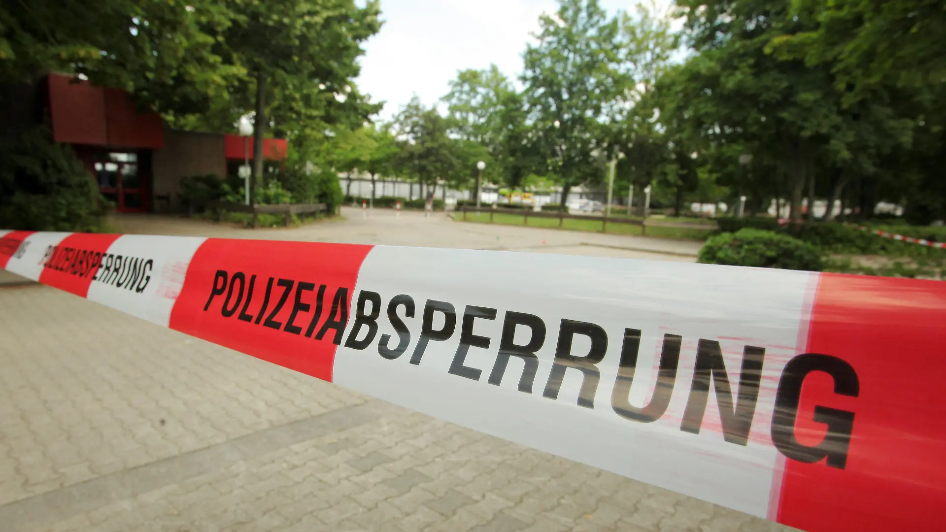 Ein Tatort vor einer Gesamtschule ist am 09.07.2013 in Hattersheim (Hessen) mit Absperrband der Polizei abgesteckt. Ein 28 Jahre alter Mann war am Vorabend in Hattersheim (Main-Taunus-Kreis) niedergestochen worden und gestorben. Passanten hatten den schwer verletzten Mann auf dem Parkplatz der Gesamtschule in Hattersheim entdeckt. Er verstarb kurz darauf in einem Frankfurter Krankenhaus. Foto: Fredrik von Erichsen/dpa (zu dpa/lhe "Hattersheim: 28-Jähriger niedergestochen, 19-Jähriger überfahren" vom 09.07.2013) +++(c) dpa - Bildfunk+++