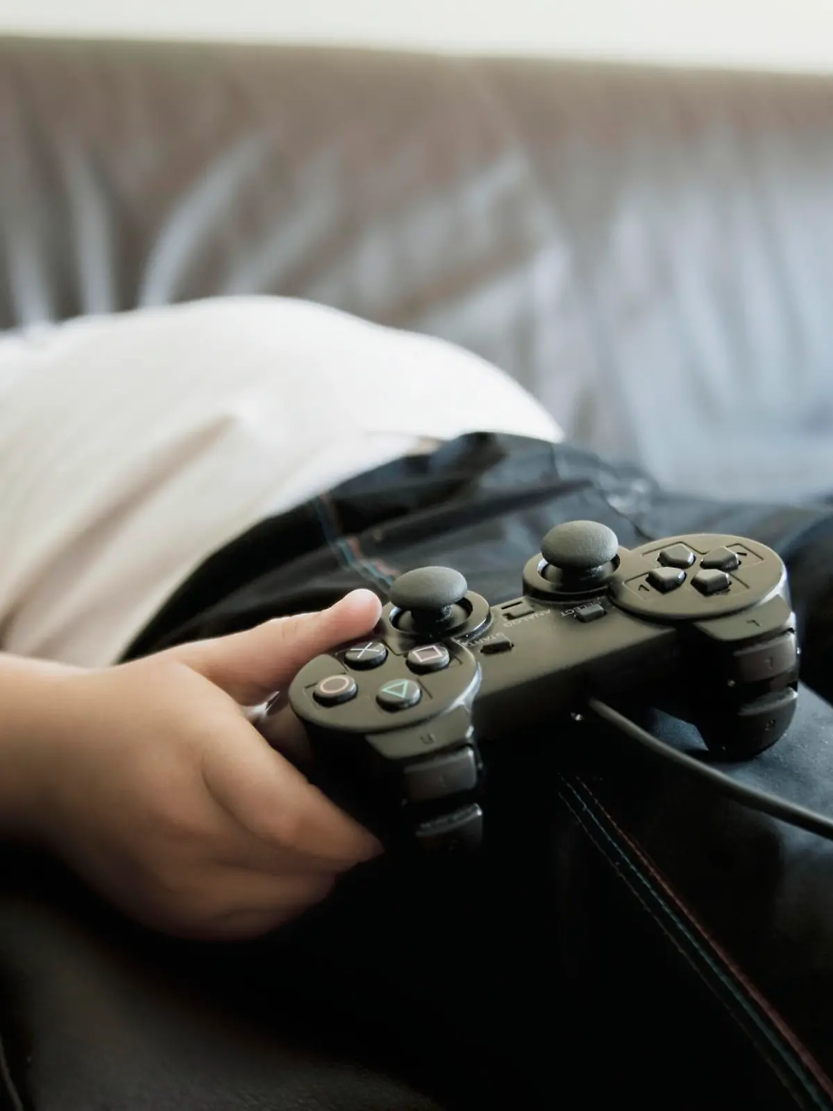 Two boys sleeping on sofa while holding games consoles