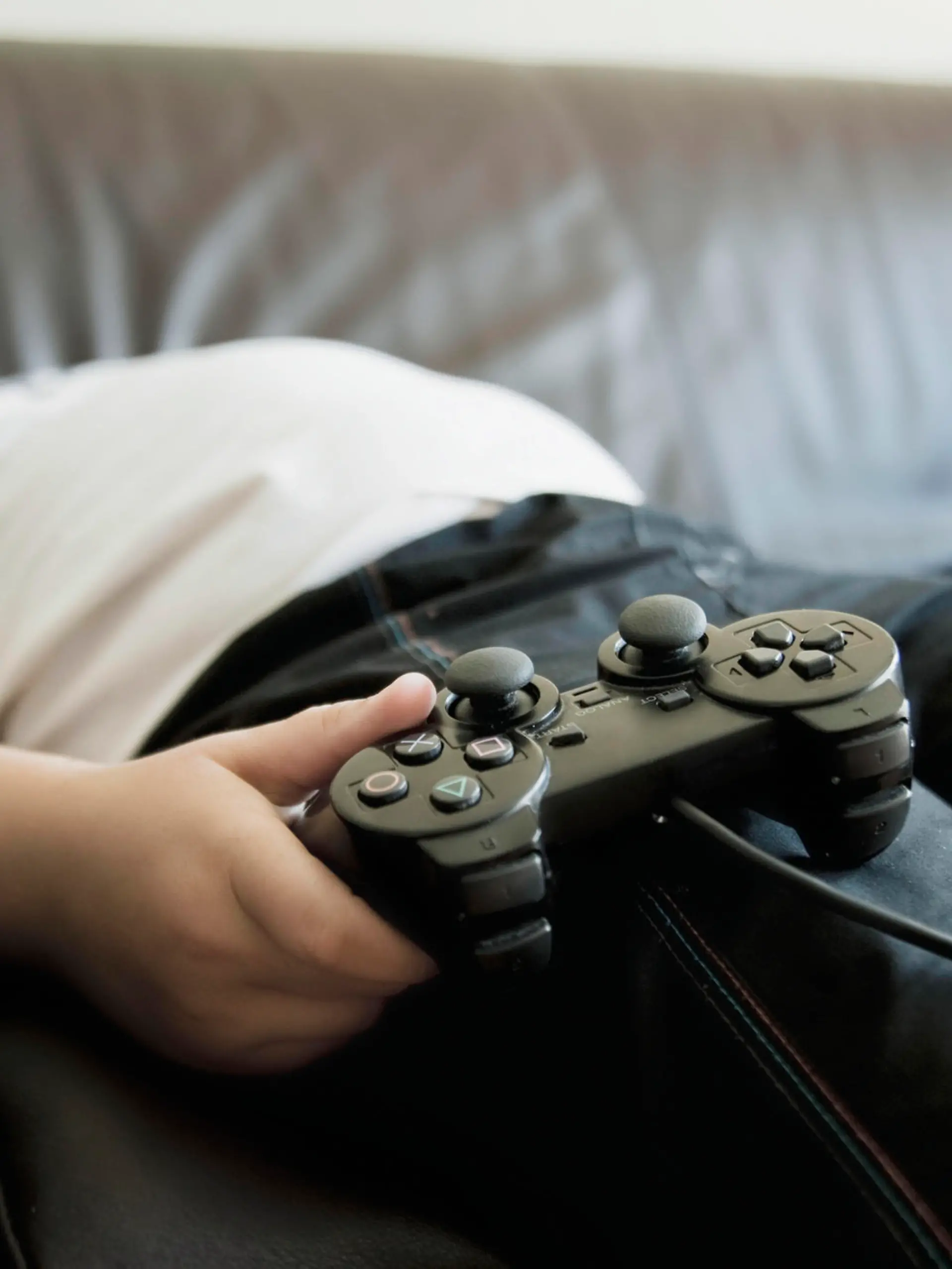 Two boys sleeping on sofa while holding games consoles