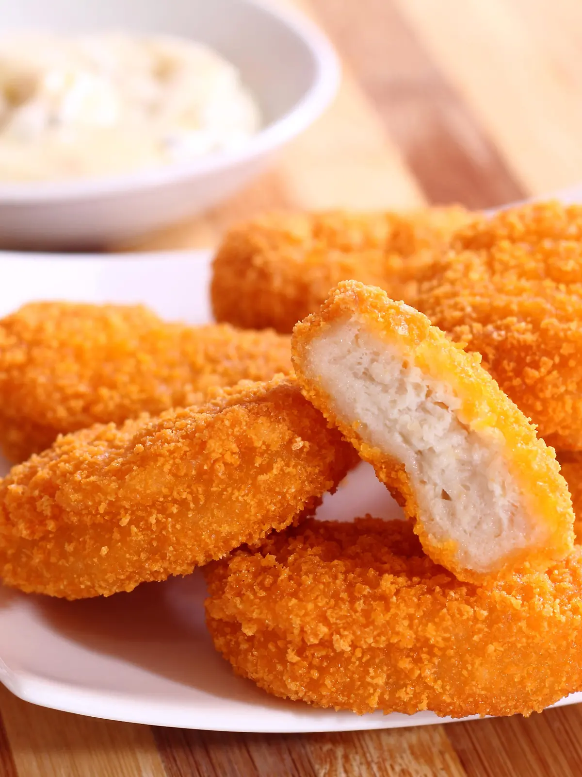 A pile of chicken nuggets on white plate with sauce