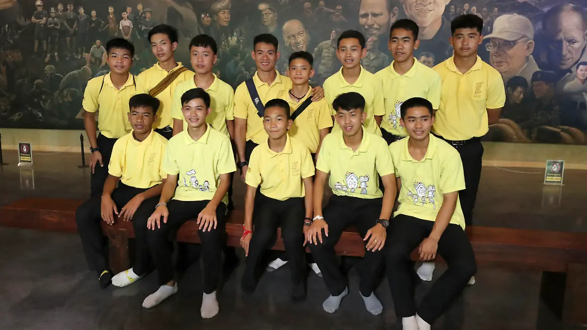 24.06.2019, Thailand, Mae Sai: Die 12 Jungs der Fußballmannschaft der «Wildschweine» aus Mae Sai und ihr ehemalige Fußballtrainer Ekkapol Chanthawong (4.v.l, hintere Reihe), die zusammen vor einem Jahr aus der überfluteten Tham-Luang-Höhle gerettet wurden, lassen sich bei einer Pressekonferenz zusammen fotografieren. Foto: Sakchai Lalit/AP/dpa +++ dpa-Bildfunk +++