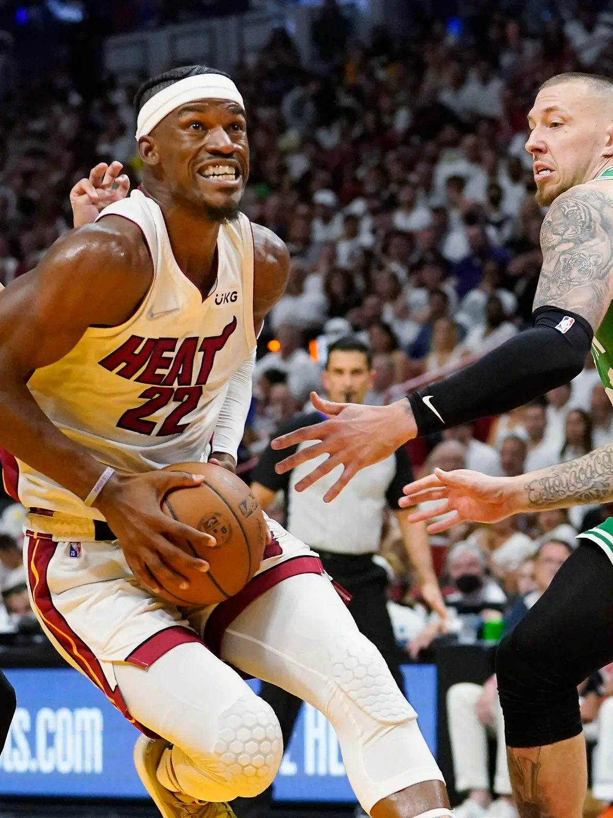 Miami Heat forward Jimmy Butler (22) drives to the basket between Boston Celtics guard Derrick White (9) and center Daniel Theis (27) during the second half of Game 1 of an NBA basketball Eastern Conference finals playoff series, Tuesday, May 17, 2022, in Miami. (AP Photo/Lynne Sladky)