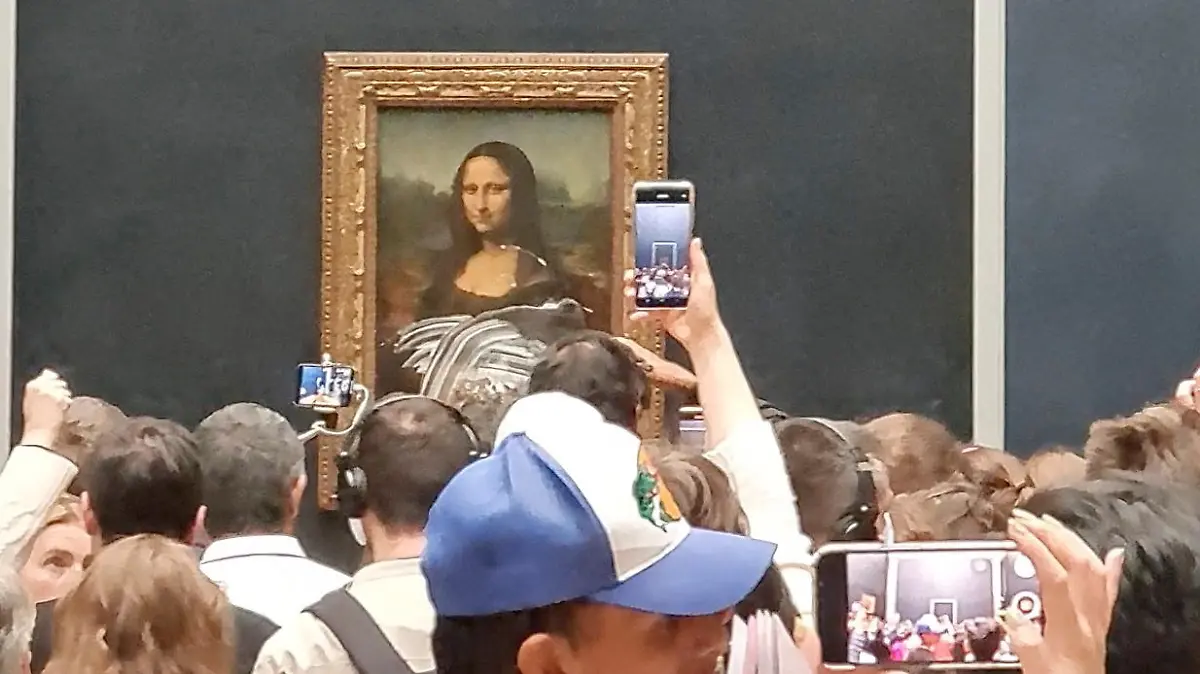 Visitors take pictures and video of the painting "Mona Lisa" after cake was smeared on the protective glass at the Lourve Museum in Paris, France May 29, 2022 in this screen grab obtained from a social media video. Twitter/@klevisl007/via REUTERS  THIS IMAGE HAS BEEN SUPPLIED BY A THIRD PARTY. MANDATORY CREDIT.