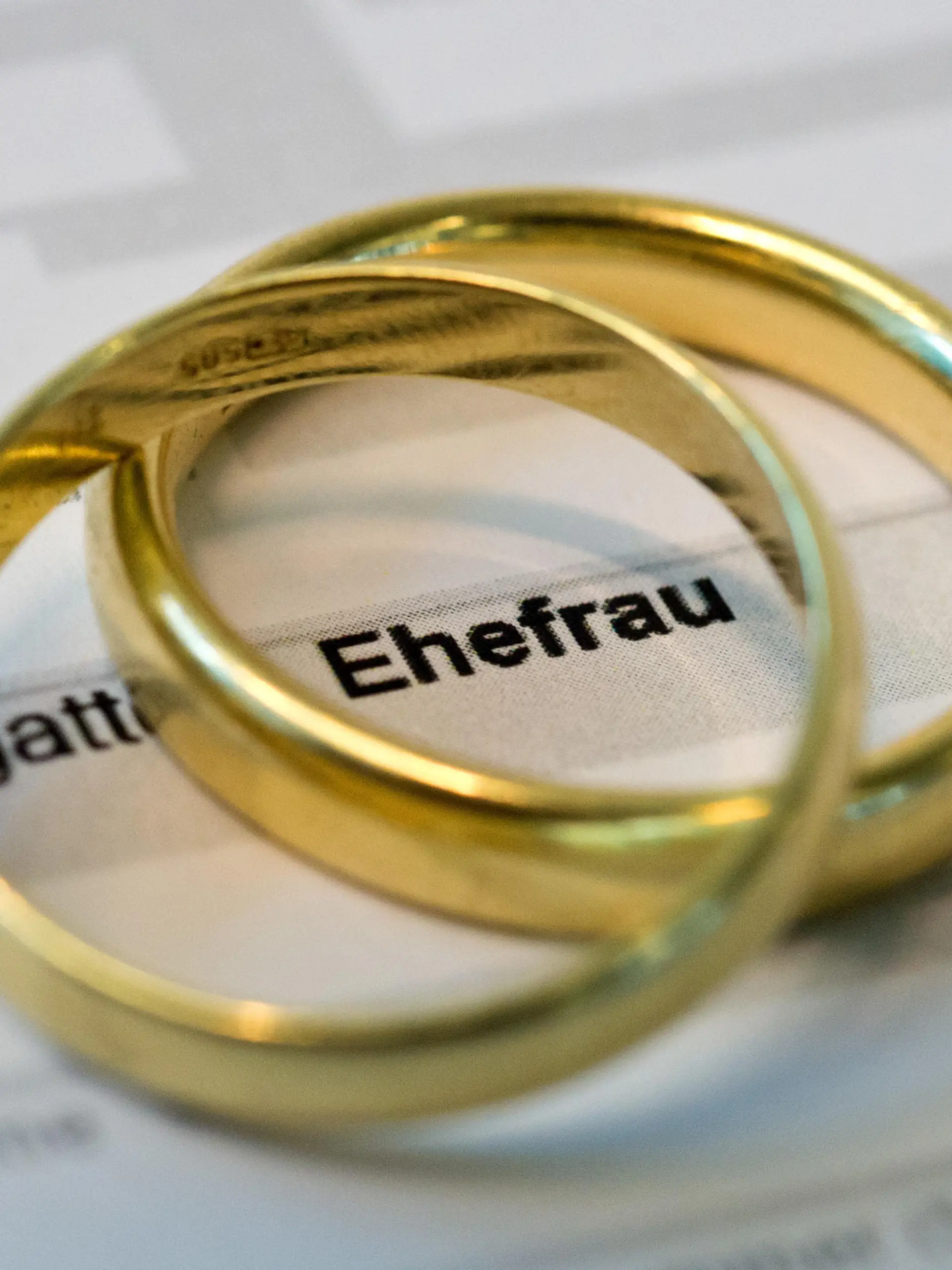 Goldene Eheringe liegen auf Formularen für die Steuererklärung.