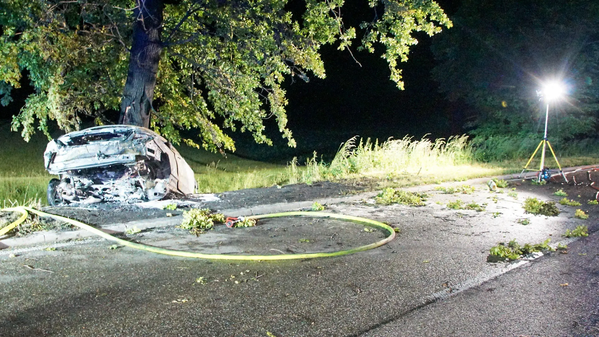 27.05.2022, Baden-Württemberg, Mühlhausen: Ein ausgebranntes Wrack steht an einem Baumstamm. Bei einem Unfall im Enzkreis sind in der Nacht zu Samstag zwei Menschen in einem Auto tödlich verunglückt. Das Fahrzeug der Insassen sei mit hoher Geschwindigkeit von der B10 von Mühlacker in Richtung Illingen gefahren, teilte die Polizei mit. Auf Höhe der Abzweigung nach Mühlhausen kam das Auto von der Bundesstraße ab, prallte gegen einen Baum und fing sofort Feuer. Foto: Waldemar Gress/Einsatz-Report24/dpa +++ dpa-Bildfunk +++