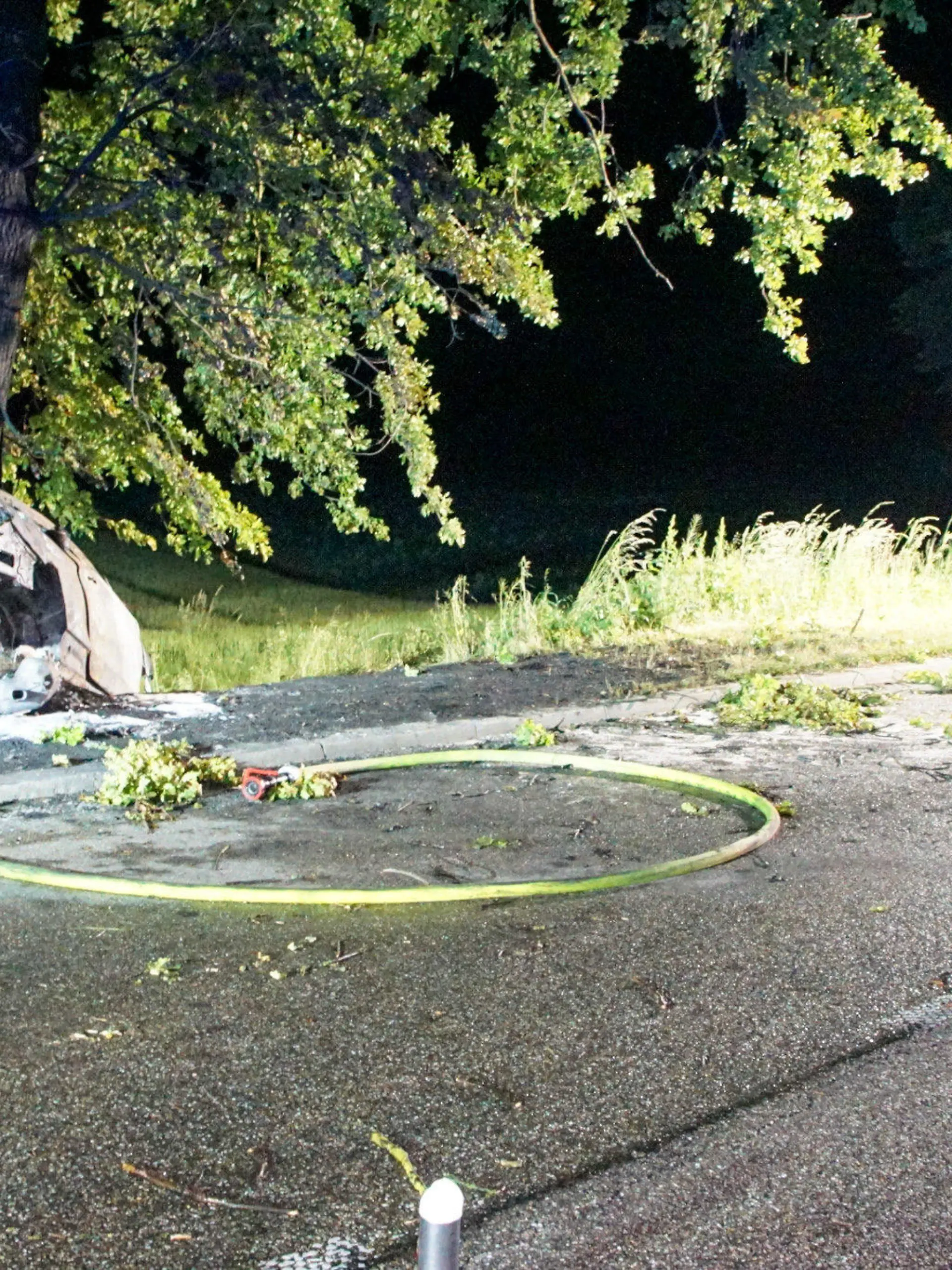 27.05.2022, Baden-Württemberg, Mühlhausen: Ein ausgebranntes Wrack steht an einem Baumstamm. Bei einem Unfall im Enzkreis sind in der Nacht zu Samstag zwei Menschen in einem Auto tödlich verunglückt. Das Fahrzeug der Insassen sei mit hoher Geschwindigkeit von der B10 von Mühlacker in Richtung Illingen gefahren, teilte die Polizei mit. Auf Höhe der Abzweigung nach Mühlhausen kam das Auto von der Bundesstraße ab, prallte gegen einen Baum und fing sofort Feuer. Foto: Waldemar Gress/Einsatz-Report24/dpa +++ dpa-Bildfunk +++