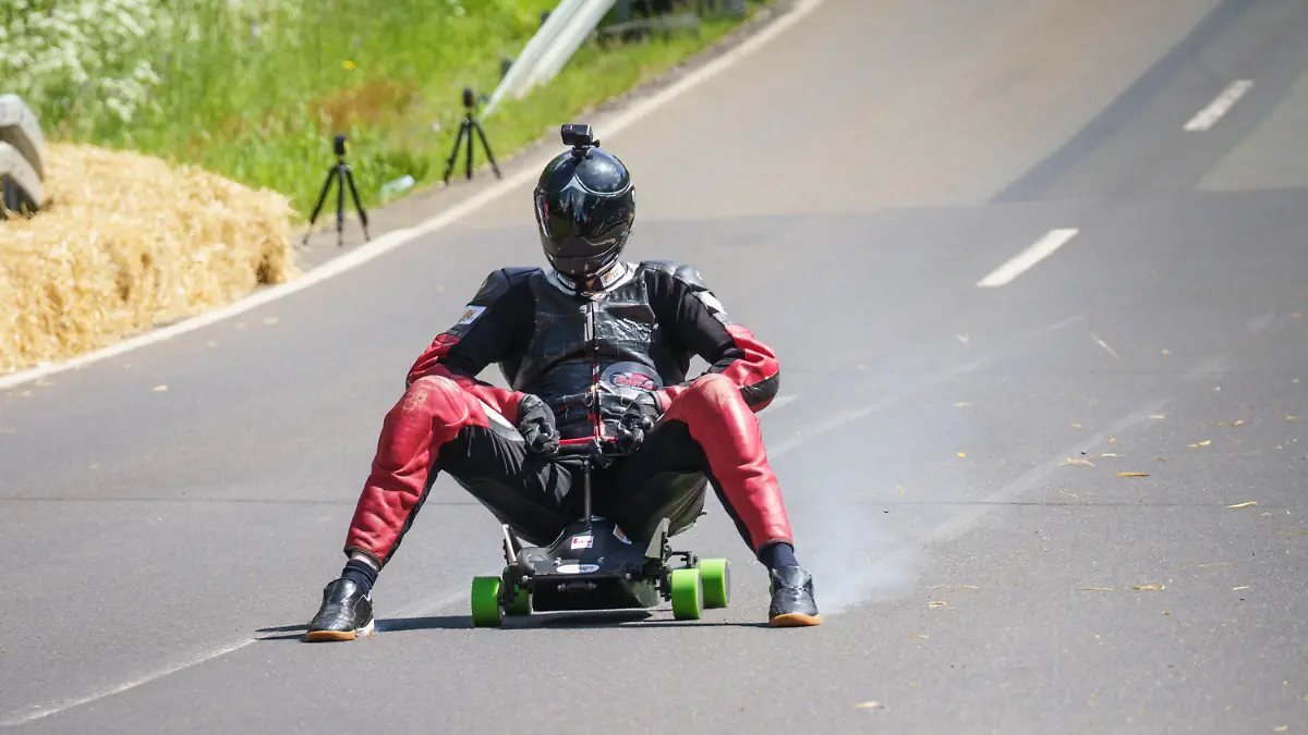 28.05.2022, Hessen, Schotten: Der Hesse Marcel Paul rast im Ortsteil Sichenhausen mit seinem modifizierten Bobbycar den Hang hinunter und bremst mit qualmenden Schuhen. Nach zwei Probeläufen erreichte der 29-Jährige mit 130,7 Stundenkilometern einen Geschwindigkeitsrekord, wie die Organisatoren berichteten. Foto: Frank Rumpenhorst/dpa +++ dpa-Bildfunk +++