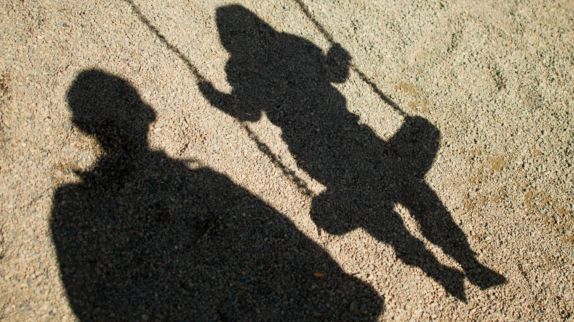 ARCHIV - 27.08.2014, Niedersachsen, Braunschweig: ILLUSTRATION - Der Schatten von einem Mann und einem schaukelnden Kind fallen auf Sand auf einem Spielplatz. (zu dpa «47-Jähriger soll Tochter missbraucht haben - Haftbefehle») Foto: Julian Stratenschulte/dpa +++ dpa-Bildfunk +++