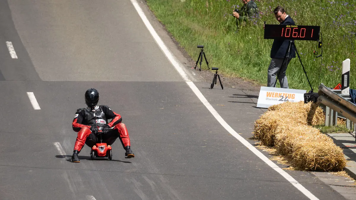 28.05.2022, Hessen, Schotten: Der Hesse Marcel Paul rast im Ortsteil Sichenhausen mit seinem regulären Bobbycar mit Gummireifen den Hang hinunter und erreicht mit 106 Stundenkilometern einen Geschwindigkeitsrekord, wie die Organisatoren berichteten und rechts auf der Messtafel steht. Das Rekord-Institut für Deutschland hat den Spitzenwert und die vorhergehende Fahrt auf einem modifizierten Bobbycar mit 130,7 Kilometern bereits anerkannt. Foto: Frank Rumpenhorst/dpa +++ dpa-Bildfunk +++
