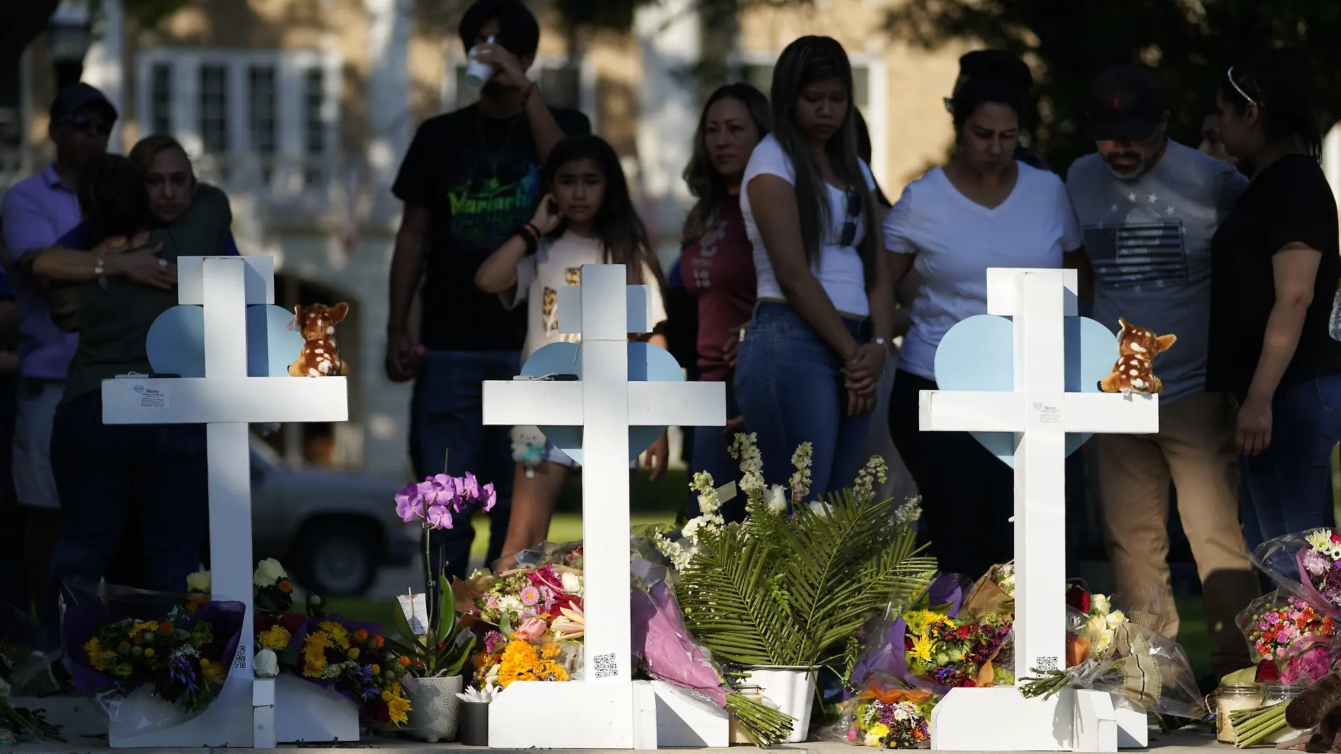 26.05.2022, USA, Uvalde: Menschen trauern um die Opfer des Massakers an einer Grundschule in Uvalde, sie stehen vor Kreuzen mit Herzen, die im Gedenken an die Opfer aufgestellt wurden. Ein 18 Jahre alter Schütze hatte am Dienstag in der Kleinstadt Uvalde 19 Schulkinder und zwei Lehrkräfte erschossen. Foto: Wu Xiaoling/XinHua/dpa +++ dpa-Bildfunk +++