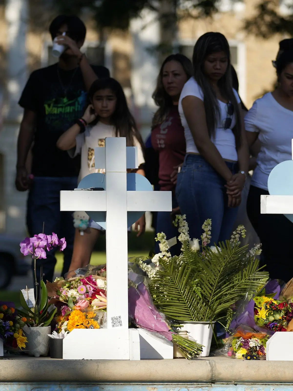 26.05.2022, USA, Uvalde: Menschen trauern um die Opfer des Massakers an einer Grundschule in Uvalde, sie stehen vor Kreuzen mit Herzen, die im Gedenken an die Opfer aufgestellt wurden. Ein 18 Jahre alter Schütze hatte am Dienstag in der Kleinstadt Uvalde 19 Schulkinder und zwei Lehrkräfte erschossen. Foto: Wu Xiaoling/XinHua/dpa +++ dpa-Bildfunk +++