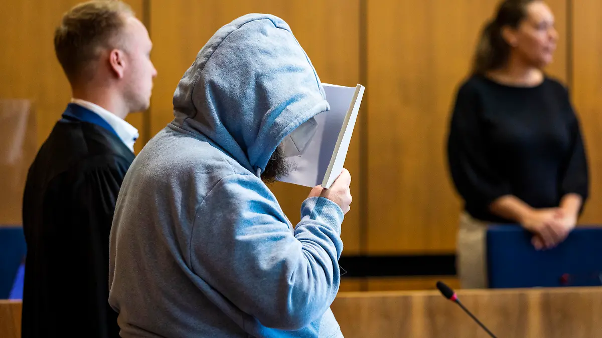 19.06.2023, Niedersachsen, Hildesheim: Der Angeklagte (M) steht beim Prozessauftakt wegen teils schweren sexuellen Missbrauchs von Kindern neben seinem Verteidiger Jonas Meese (l) in einem Saal des Landgerichts Hildesheim. Dem Angeklagten wird vorgeworfen, sich gegenüber Eltern als vertrauenswürdige Aufsichtsperson ausgegeben und dann in seiner Wohnung insgesamt 16 Straftaten begangen zu haben. Die betroffenen Kinder sollen nach Gerichtsangaben etwa zwischen fünf und zwölf Jahre alt gewesen sein. Foto: Moritz Frankenberg/dpa +++ dpa-Bildfunk +++