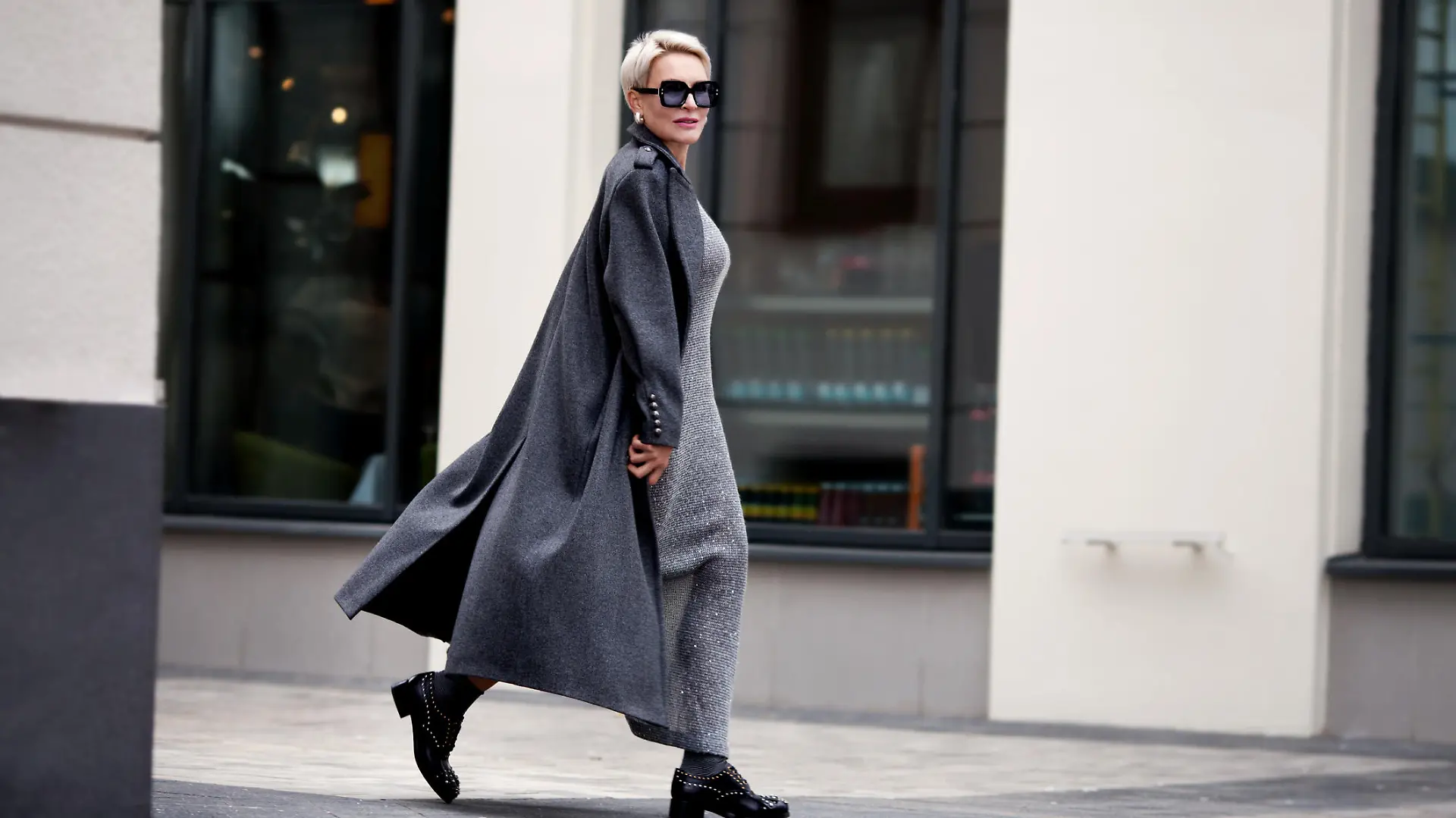 Frau trägt schickes Maxikleid mit Jacke und Sonnenbrille.