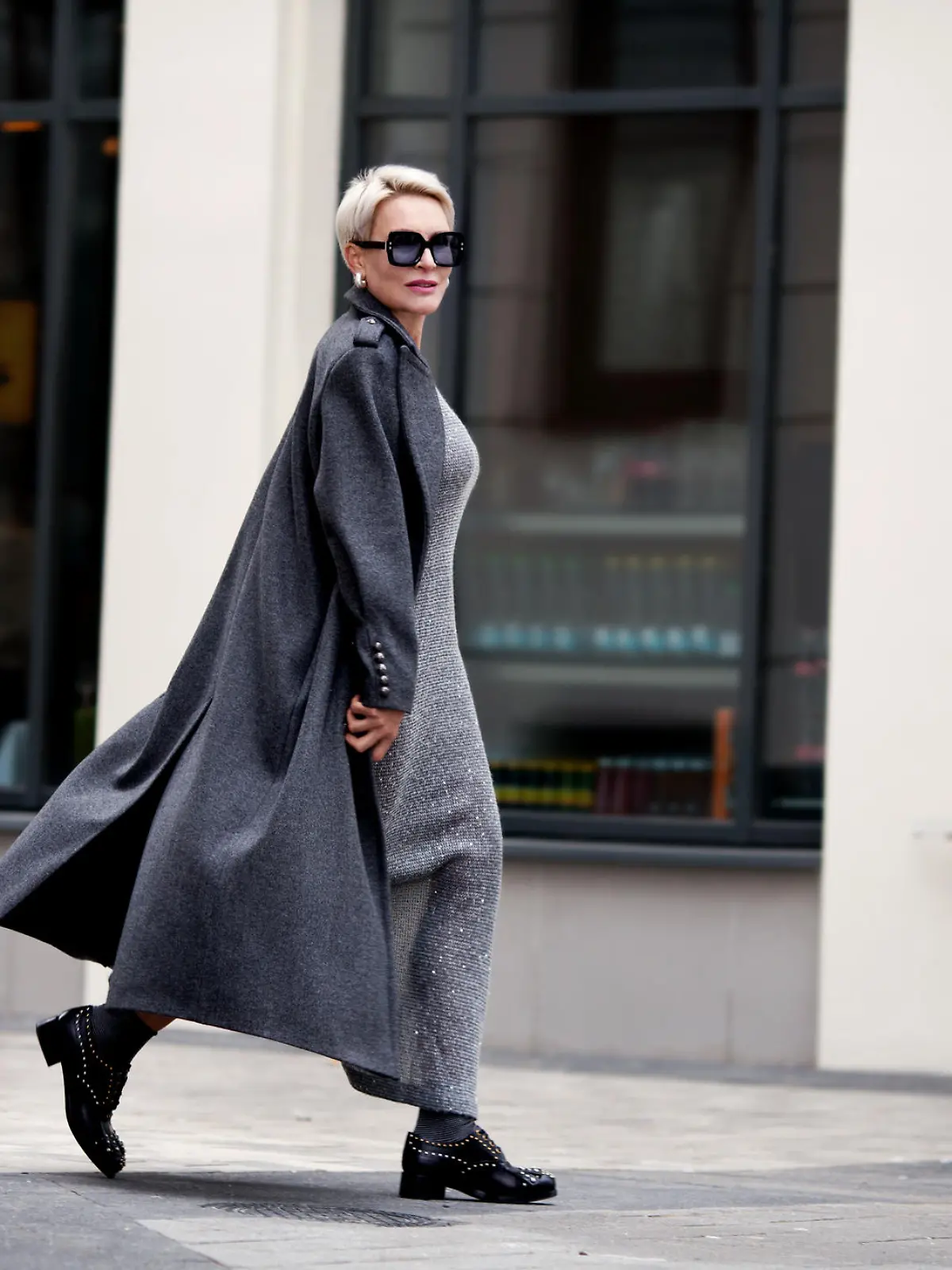 Frau trägt schickes Maxikleid mit Jacke und Sonnenbrille.
