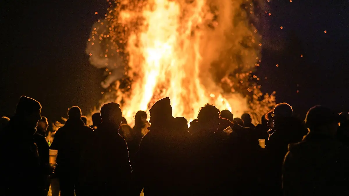 Menschen stehen vor einem Feuer.