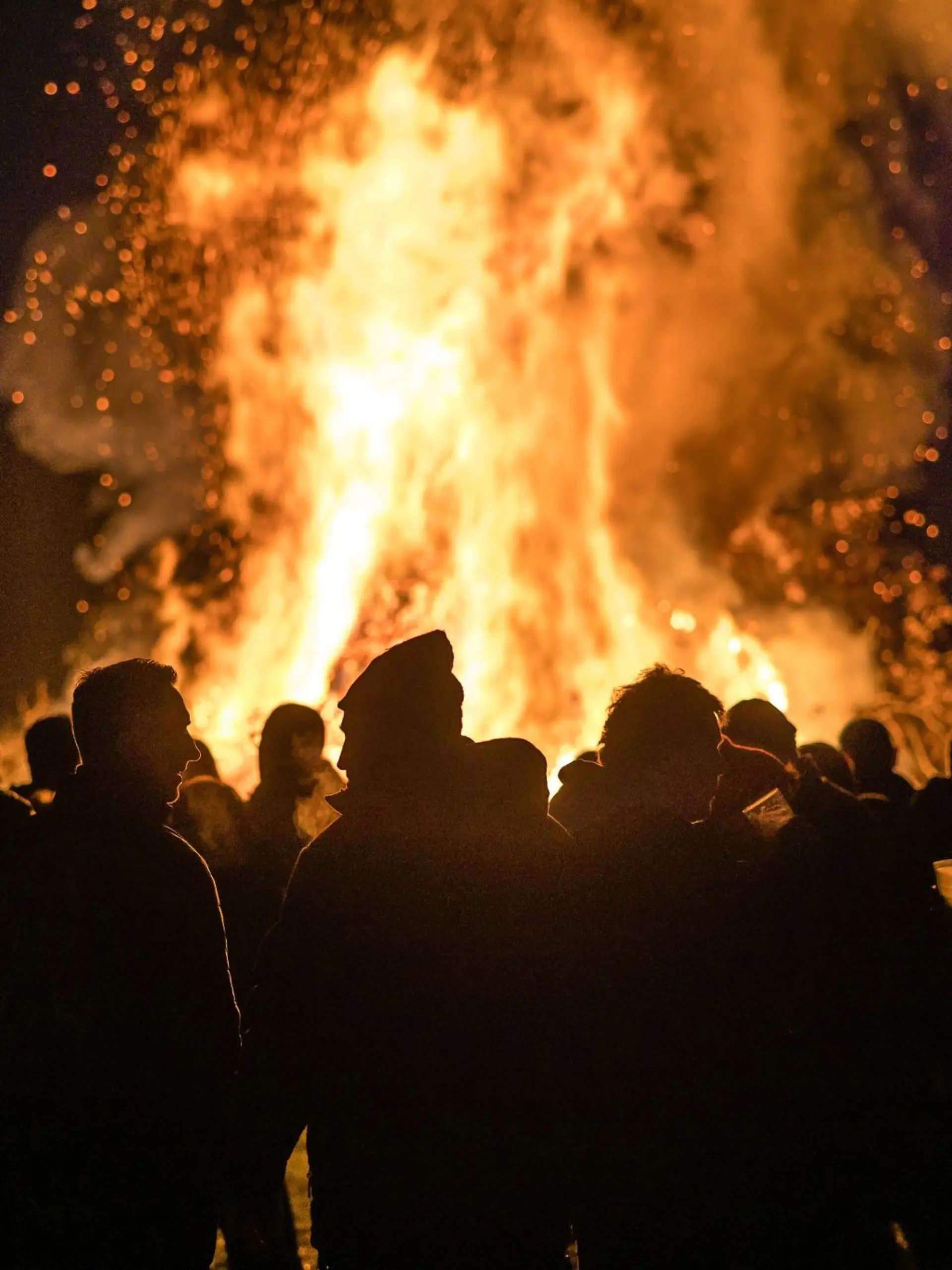 Menschen stehen vor einem Feuer.