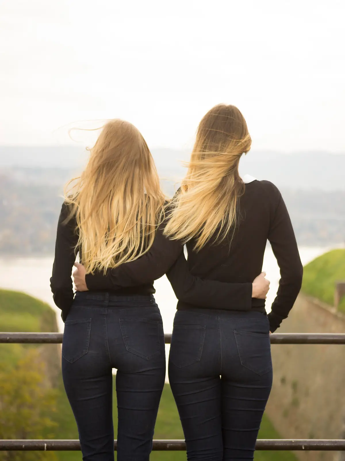Two identical teenage girlfriends, shot from back. Rear view