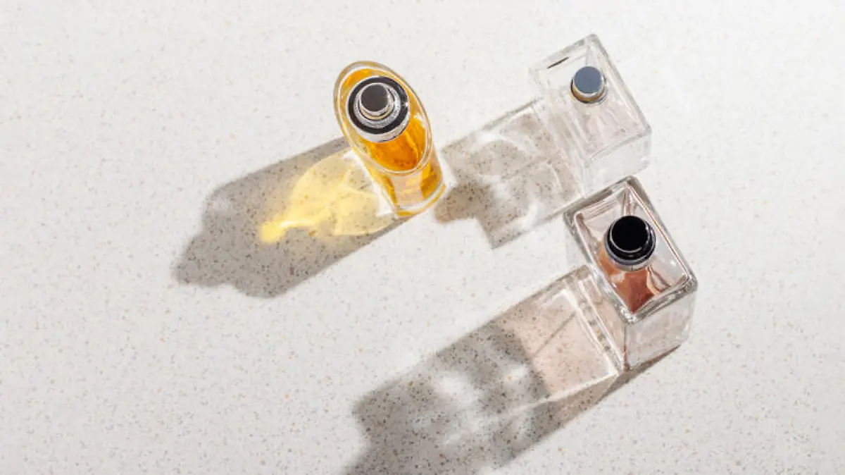 A group of perfume bottles on a white stone background on a sunny day