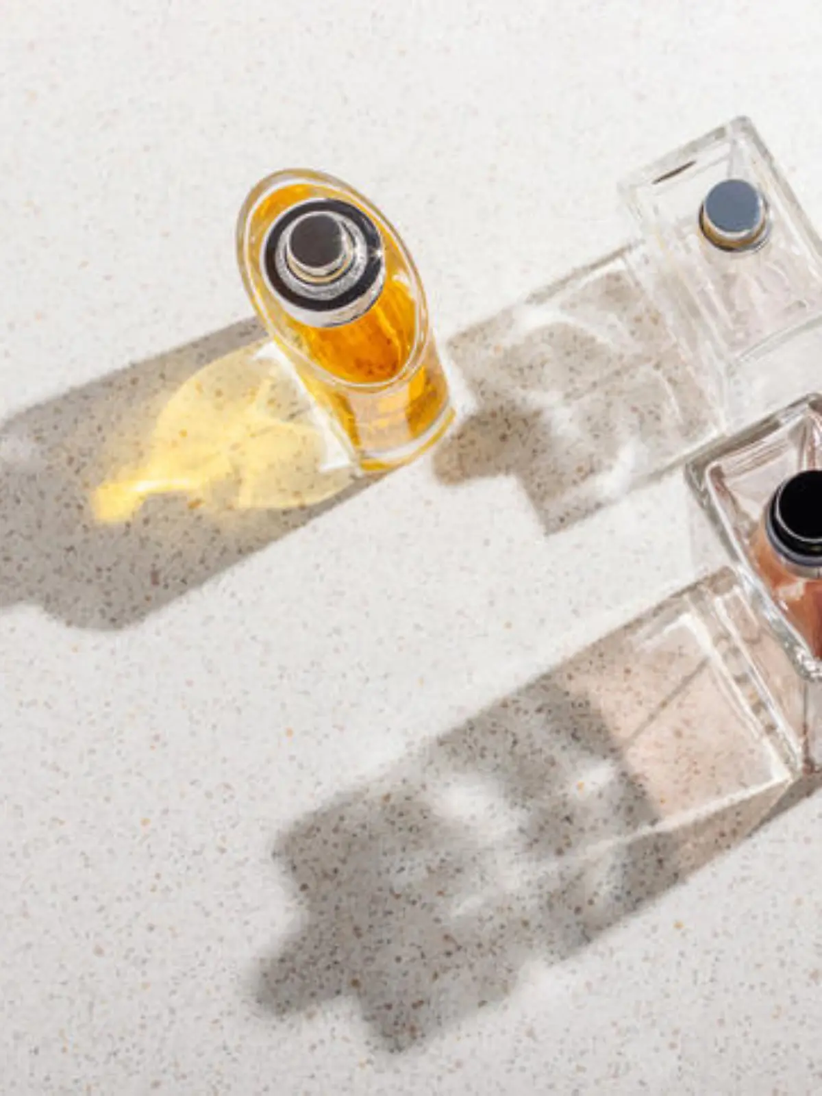 A group of perfume bottles on a white stone background on a sunny day