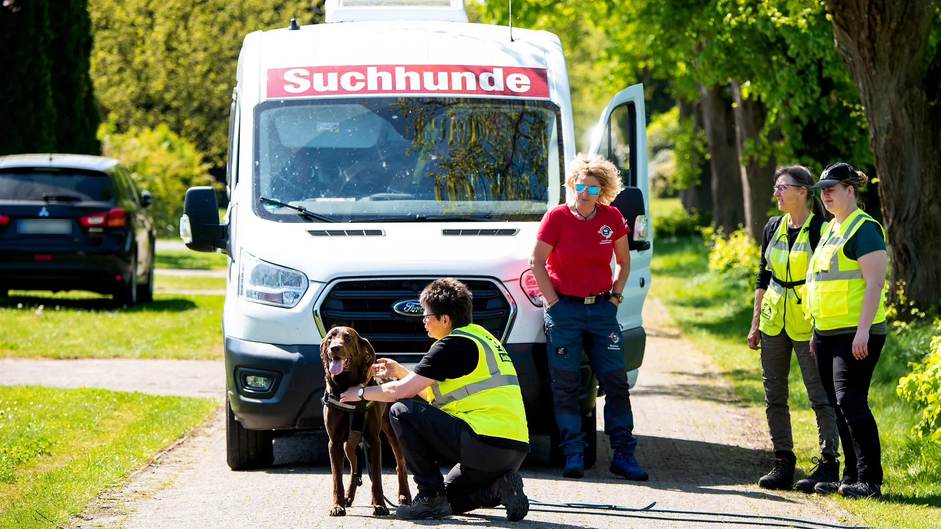 01.05.2024, Niedersachsen, Behrste: Ein Hund der K-9 Suchhunde Elbe-Weser wird für die Suche nach einem vermissten Jungen in einem Wohngebiet vorbereitet. Der sechs Jahre alte Arian aus Elm bleibt auch nach über einer Woche vermisst. Foto: Daniel Bockwoldt/dpa - ACHTUNG: PKW-Kennzeichen wurde aus rechtlichen Gründen gepixelt +++ dpa-Bildfunk +++