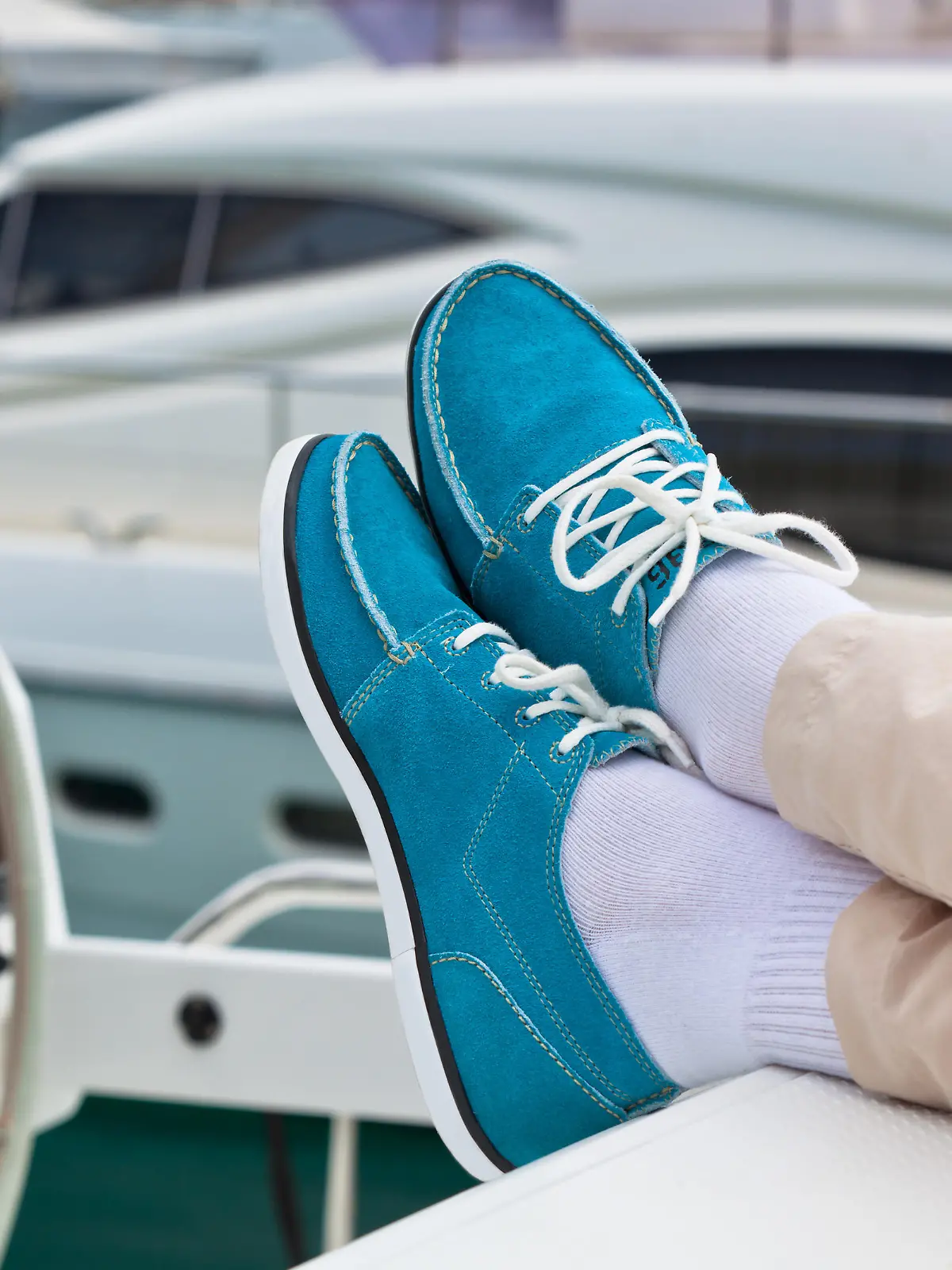 A pair of human legs in pants and bright blue topsiders on yacht deck background. Yachting