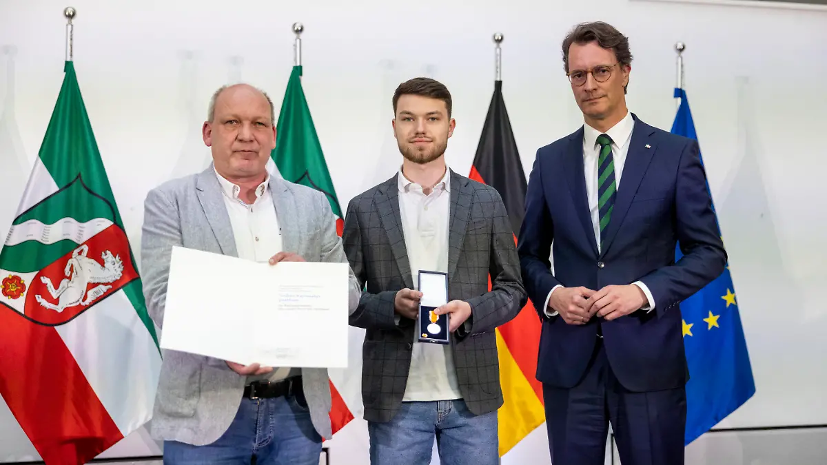 03.05.2024, Nordrhein-Westfalen, Düsseldorf: Hendrik Wüst (CDU, r), Ministerpräsident von Nordrhein-Westfalen, steht neben dem Sohn von Jochen Naßmacher, Rico Naßmacher, und dem Bruder Frank Naßmacher. Jochen Naßmacher aus Lengerich half am 30. November 2022 einer Kollegin, die von einem Mann belästigt wurde. Dabei wurde er von dem Mann mit einem Messer angegriffen und starbt zwei Tage später an seinen Verletzungen. Die posthume Auszeichnung wird von seinem Sohn und seinem Bruder entgegengenommen. Foto: Thomas Banneyer/dpa +++ dpa-Bildfunk +++