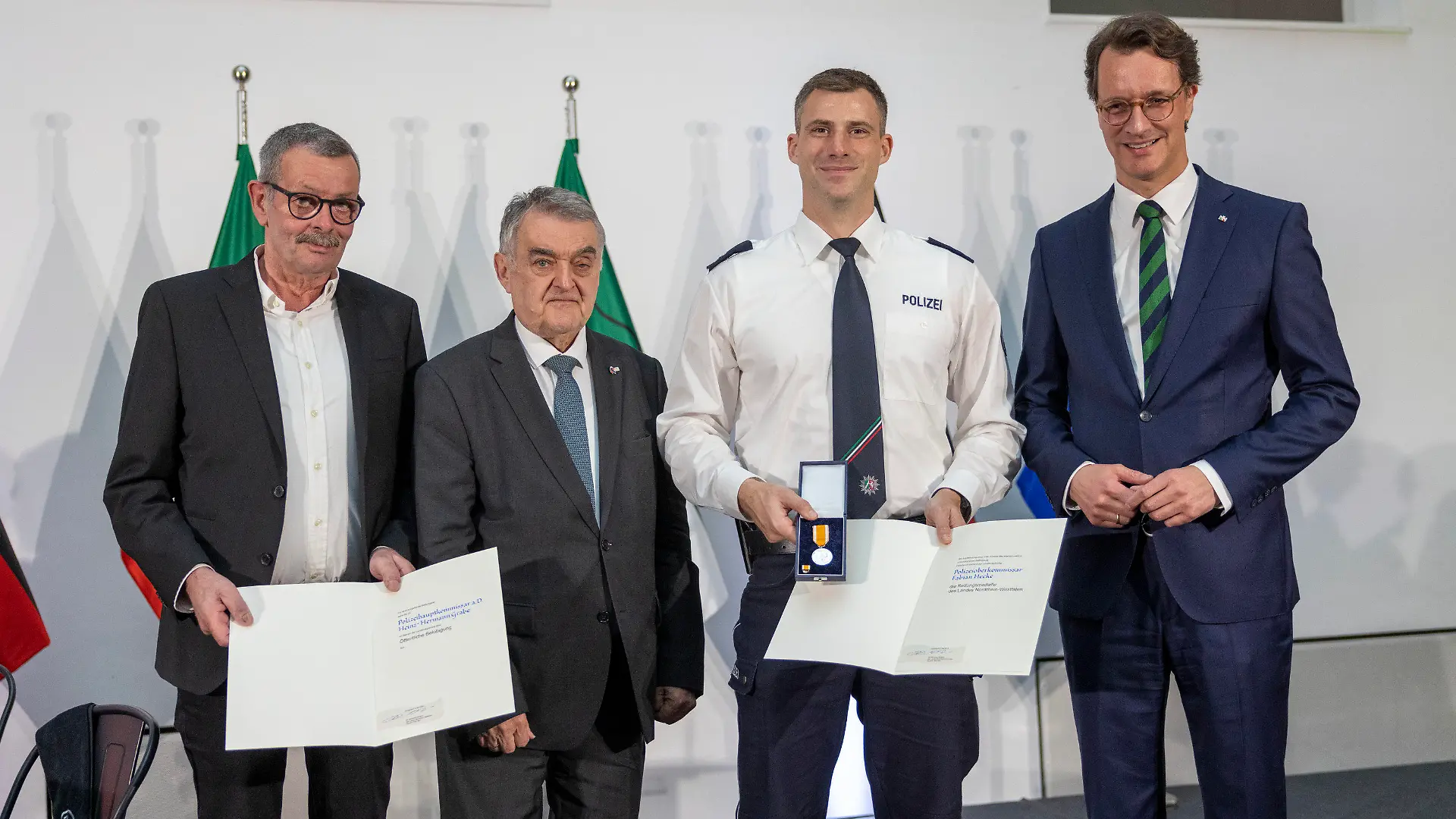 03.05.2024, Nordrhein-Westfalen, Düsseldorf: Hendrik Wüst (CDU, r), Ministerpräsident von Nordrhein-Westfalen steht mit Herbert Reul (2 v.l.) Minister des Innern des Landes Nordrhein-Westfalen neben Polizeioberkommissar Fabian Heeke aus Osnabrück, der am 1. April 2022 einen Mann vor dem Ertrinken aus dem Dortmund-Ems-Kanal rettete. Polizeihauptkommissar a.D. Heinz-Hermann Grabe (l) aus Nottuln unterstützte die Rettung und erhält dafür eine  ffentliche Belobigung. Foto: Thomas Banneyer/dpa +++ dpa-Bildfunk +++
