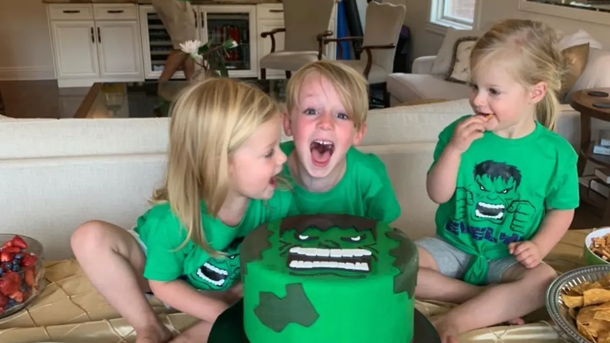 Drei kleine Kinder lachen in die Kamera.