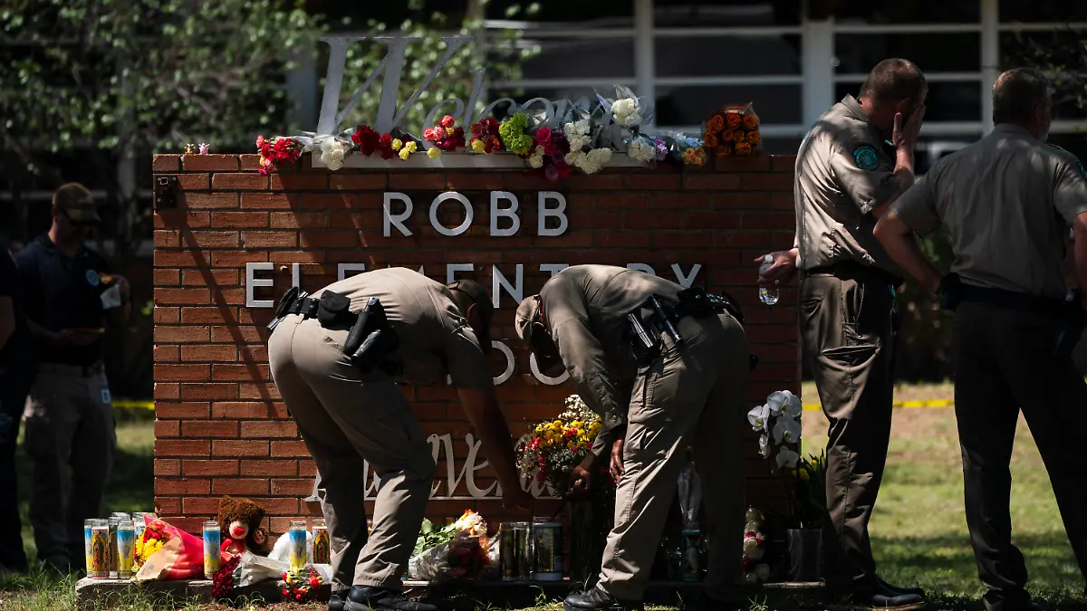 25.05.2022, USA, Uvalde: Zwei Polizisten zünden vor der Robb Elementary School eine Kerze an. Ein 18-jähriger hat bei einem Amoklauf in einer Grundschule im US-Bundesstaat Texas mehrere Menschen getötet. Foto: Jae C. Hong/AP/dpa +++ dpa-Bildfunk +++