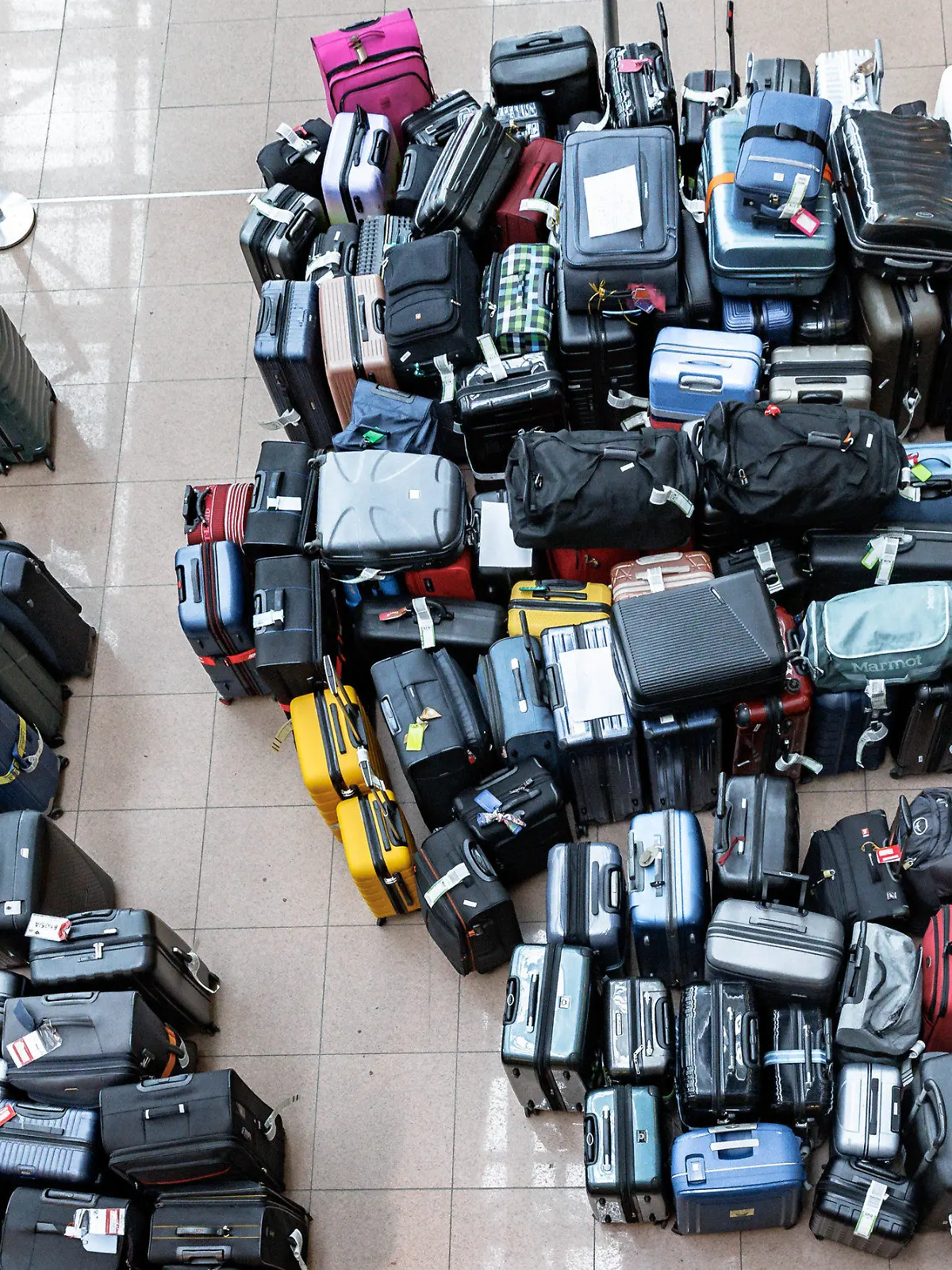 05.05.2024, Hamburg: Fluggepäck liegt an einem Sammelpunkt in einer Abflughalle des Flughafens Hamburg. Wegen eines Ausfalls der Gepäckanlage muss das Fluggepäck von Hand sortiert und dann zu den Maschinen gebracht werden. Foto: Markus Scholz/dpa +++ dpa-Bildfunk +++