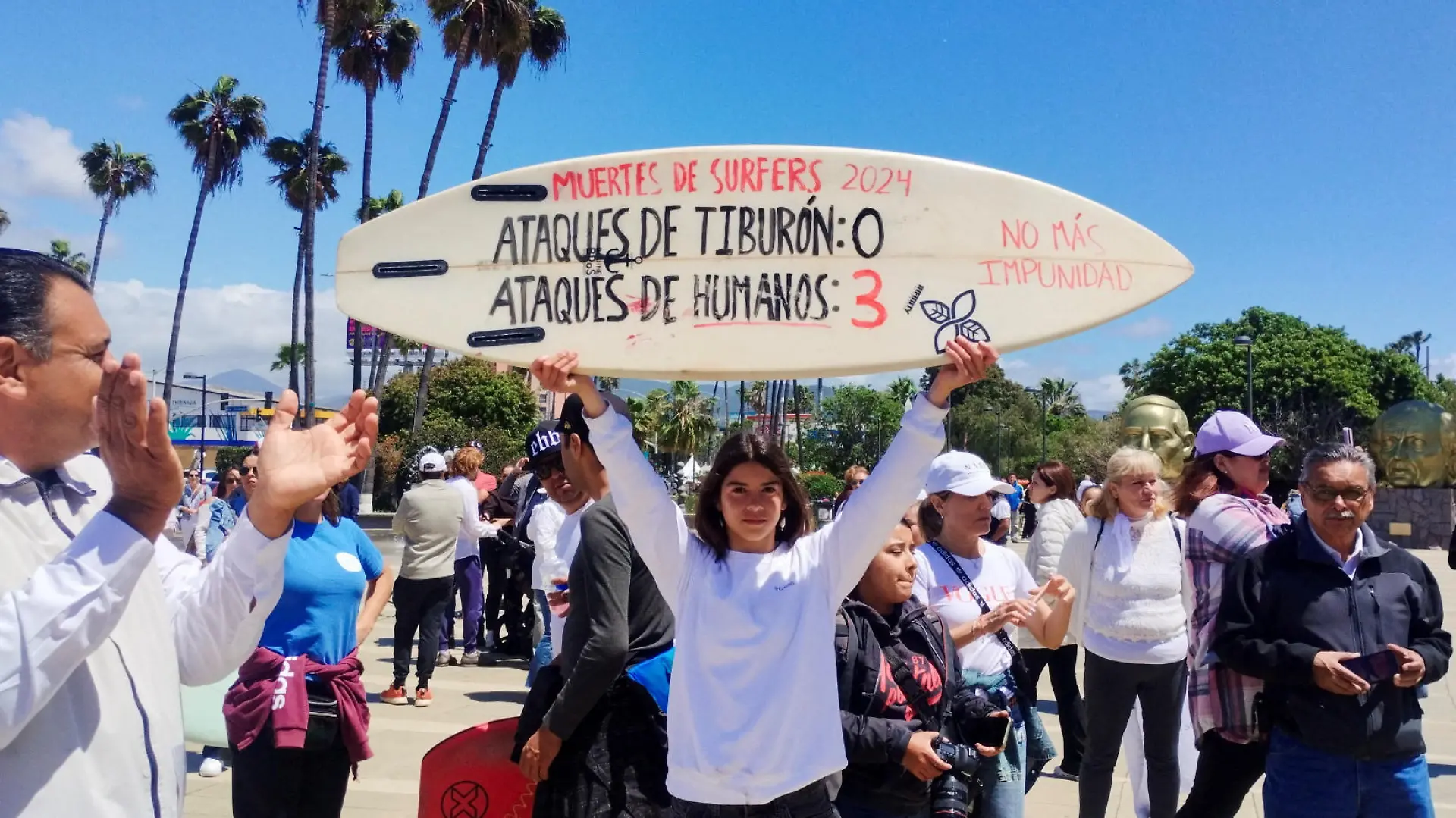 A woman holds a surfboard with the writing “Surfer deaths-Shark attacks: 0 and Human attacks: 3” during a protest as Mexican authorities confirmed U.S. and Australian tourists who went missing in northern Mexico last week are dead after their bodies were identified by their parents, in Ensenada, Mexico May 5, 2024. REUTERS/Francisco Javier Cruz