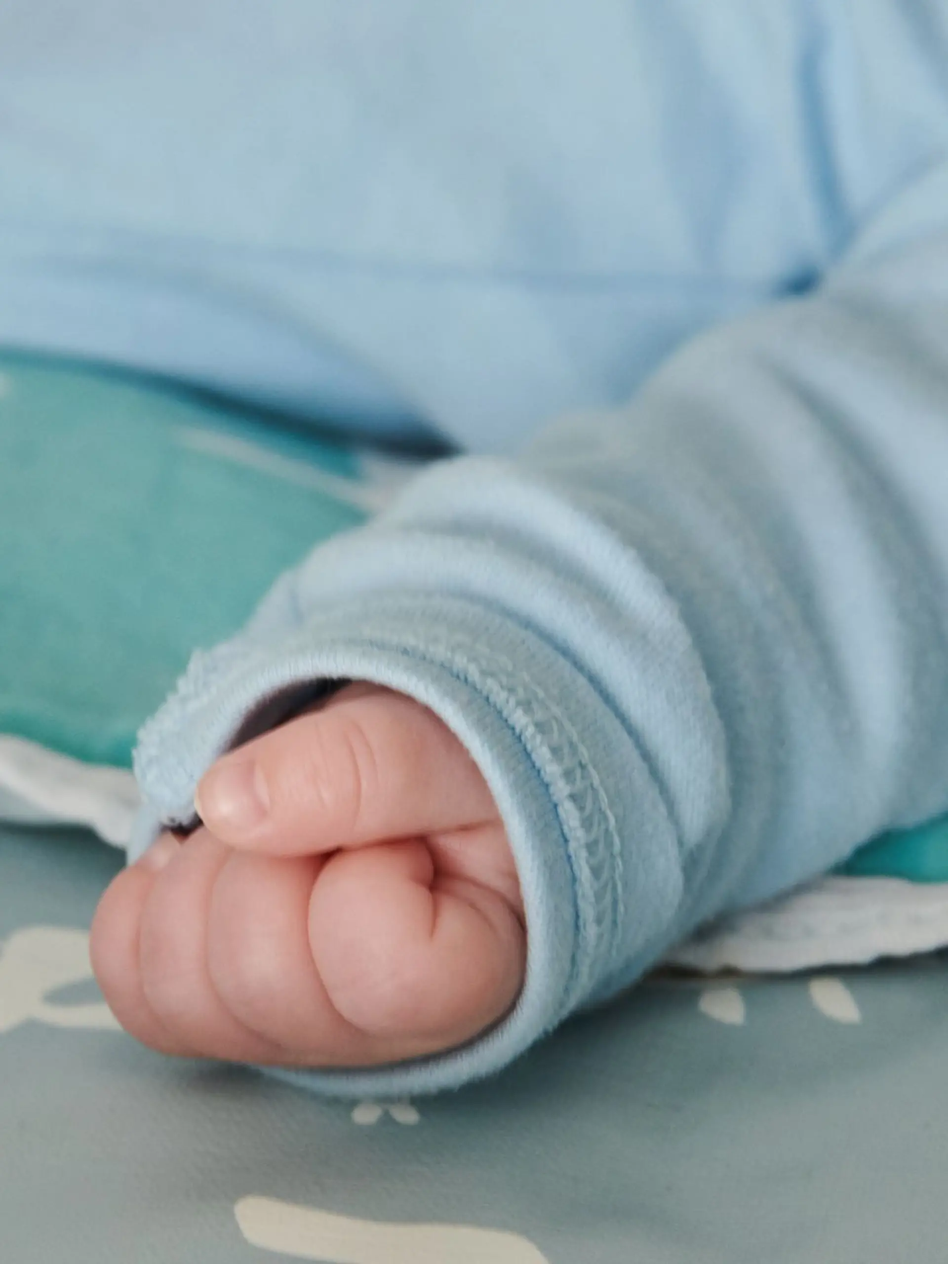 Ein wenige Wochen altes Baby ballt seine Hand zu einer kleinen Faust.