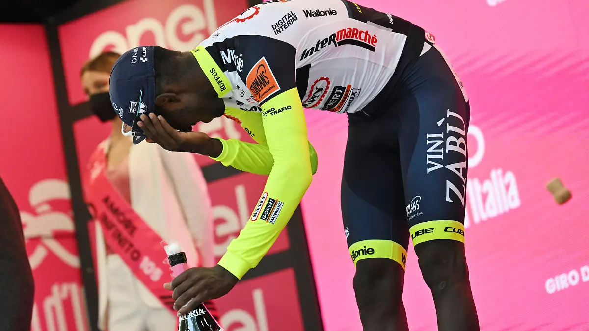 17.05.2022, Italien, Jesi: Radsport: UCI WorldTour - Giro d·Italia, Pescara - Jesi (196,00 km), 10. Etappe, Siegerehrung: Biniam Girmay aus Eritrea berührt sein Auge, nachdem er auf dem Podium Sekt verspritzt hatte, um den Sieg der 10. Etappe des Giro D'Italia von Pescara nach Jesi, Italien, zu feiern. Girmay wurde anschließend in ein örtliches Krankenhaus gebracht. Foto: Massimo Paolone/LaPresse/AP/dpa +++ dpa-Bildfunk +++