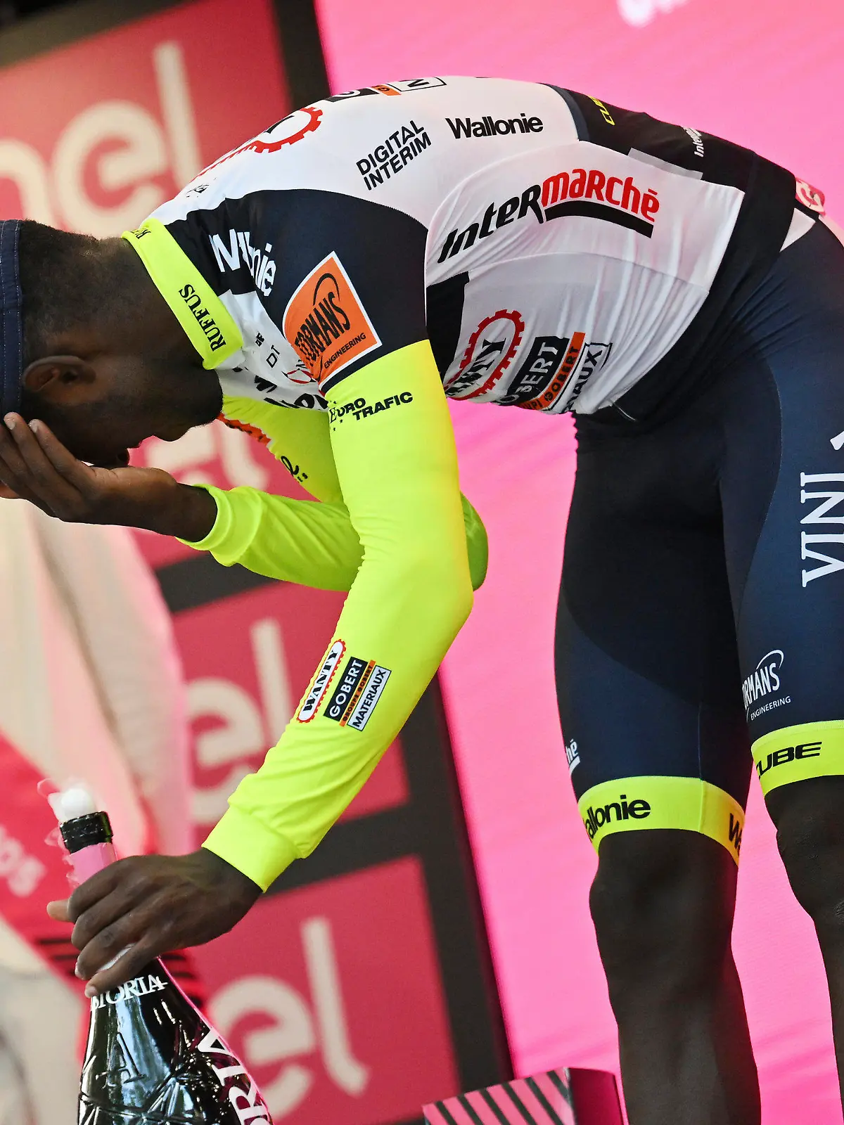 17.05.2022, Italien, Jesi: Radsport: UCI WorldTour - Giro d·Italia, Pescara - Jesi (196,00 km), 10. Etappe, Siegerehrung: Biniam Girmay aus Eritrea berührt sein Auge, nachdem er auf dem Podium Sekt verspritzt hatte, um den Sieg der 10. Etappe des Giro D'Italia von Pescara nach Jesi, Italien, zu feiern. Girmay wurde anschließend in ein örtliches Krankenhaus gebracht. Foto: Massimo Paolone/LaPresse/AP/dpa +++ dpa-Bildfunk +++